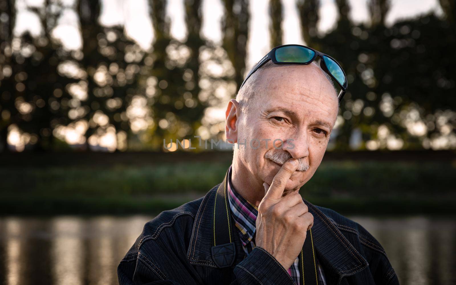 Life style concept. Old man. Portrait of a wise, skeptical and tired of life elderly man on a natural background