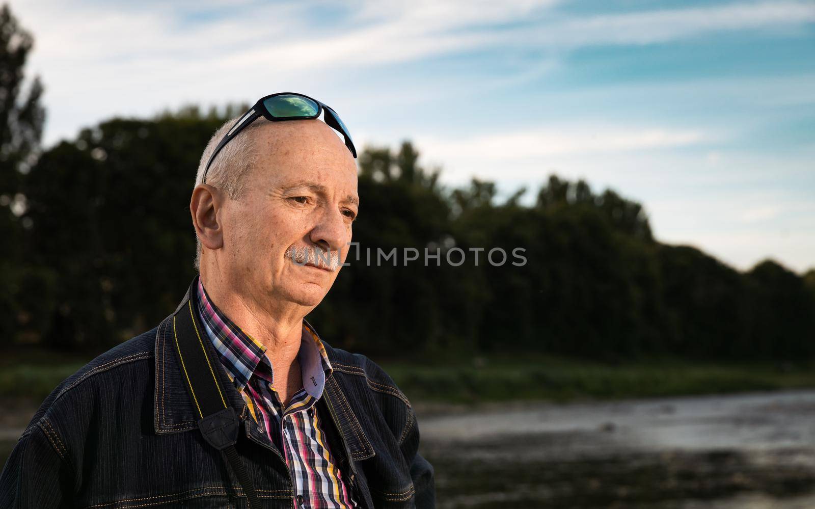 Life style concept. Old man. Portrait of a wise, skeptical and tired of life elderly man on a natural background