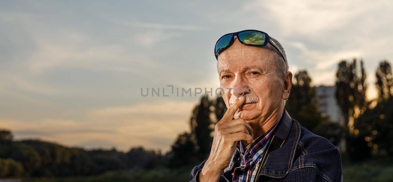 Life style concept. Old man. Portrait of a wise, skeptical and tired of life elderly man on a natural background