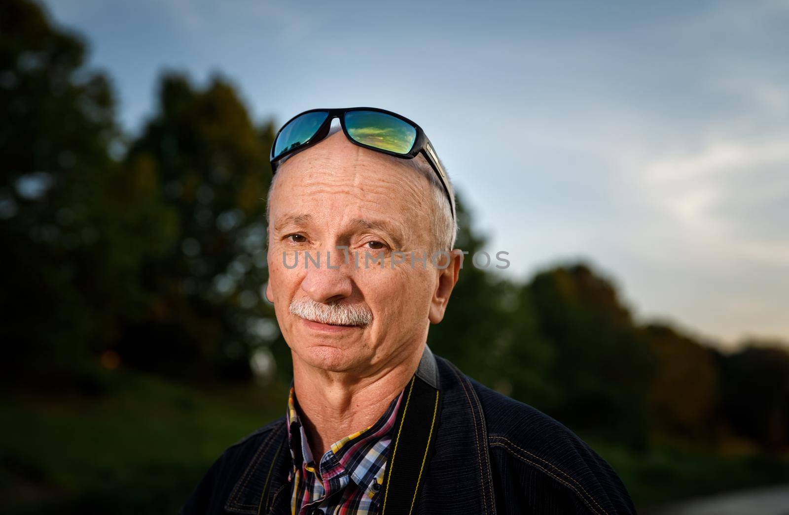 Life style concept. Old man. Portrait of a wise, skeptical and tired of life elderly man on a natural background