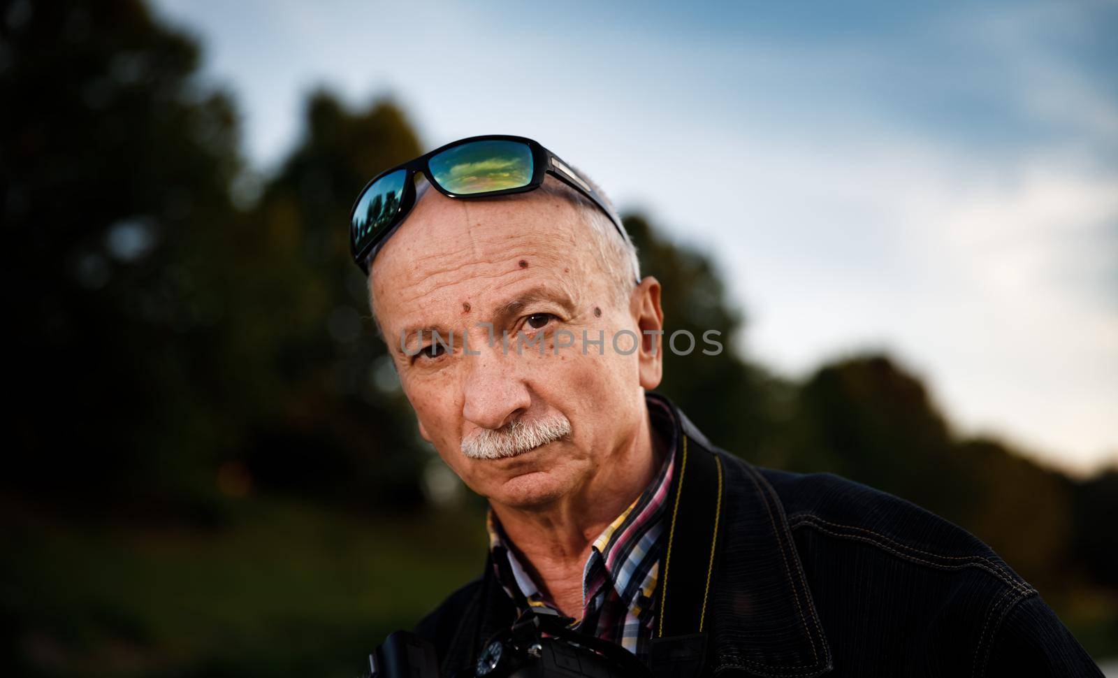 Life style concept. Old man. Portrait of a wise, skeptical and tired of life elderly man on a natural background