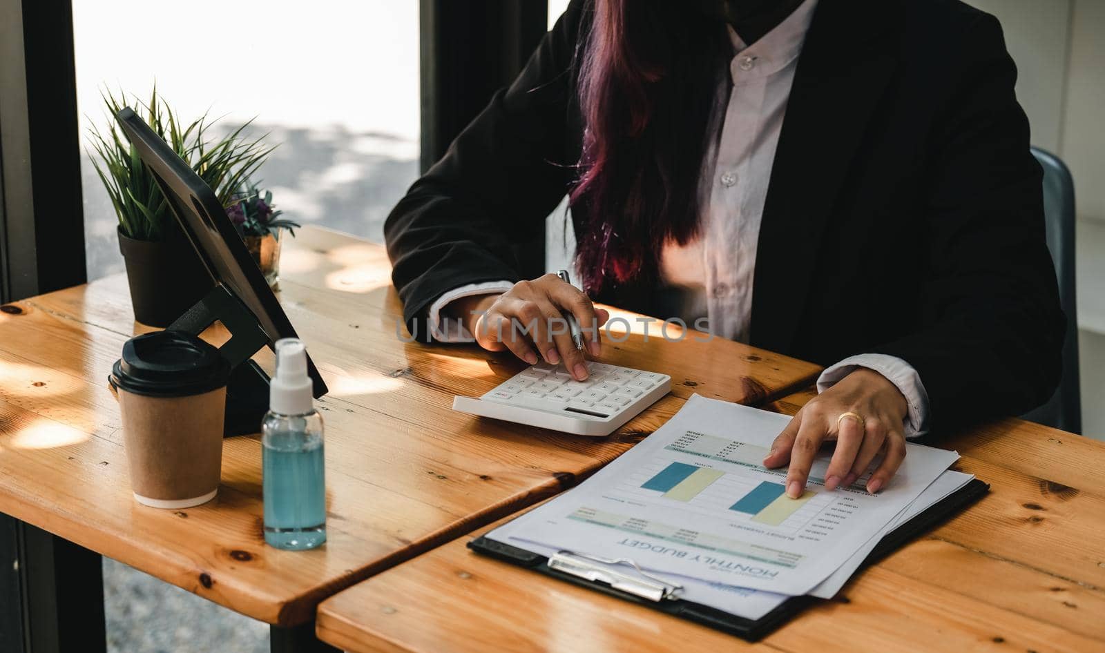 Close up woman hand using calculator to calculate the company's financial results on the wooden table in the office and business work background, tax, accounting, statistics, and analytical research