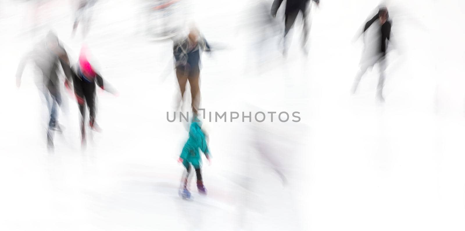 Motion blurred abstract image of people skating on an ice rink. Ice-skating people.