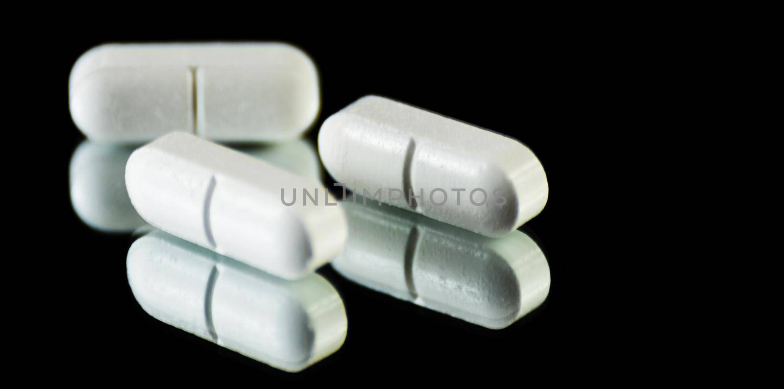 scattered tablets on a black background, pills reflected in the mirror by Q77photo