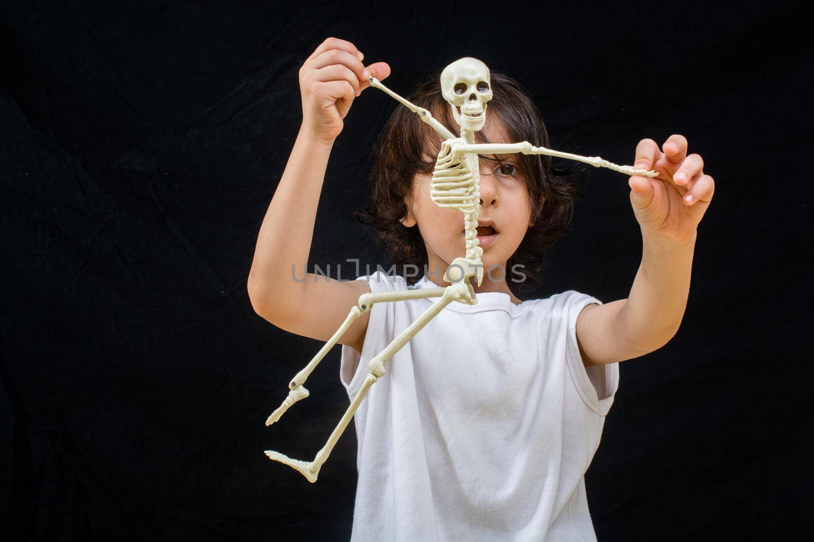 Little boy holding a small size artificial skeleton in hand