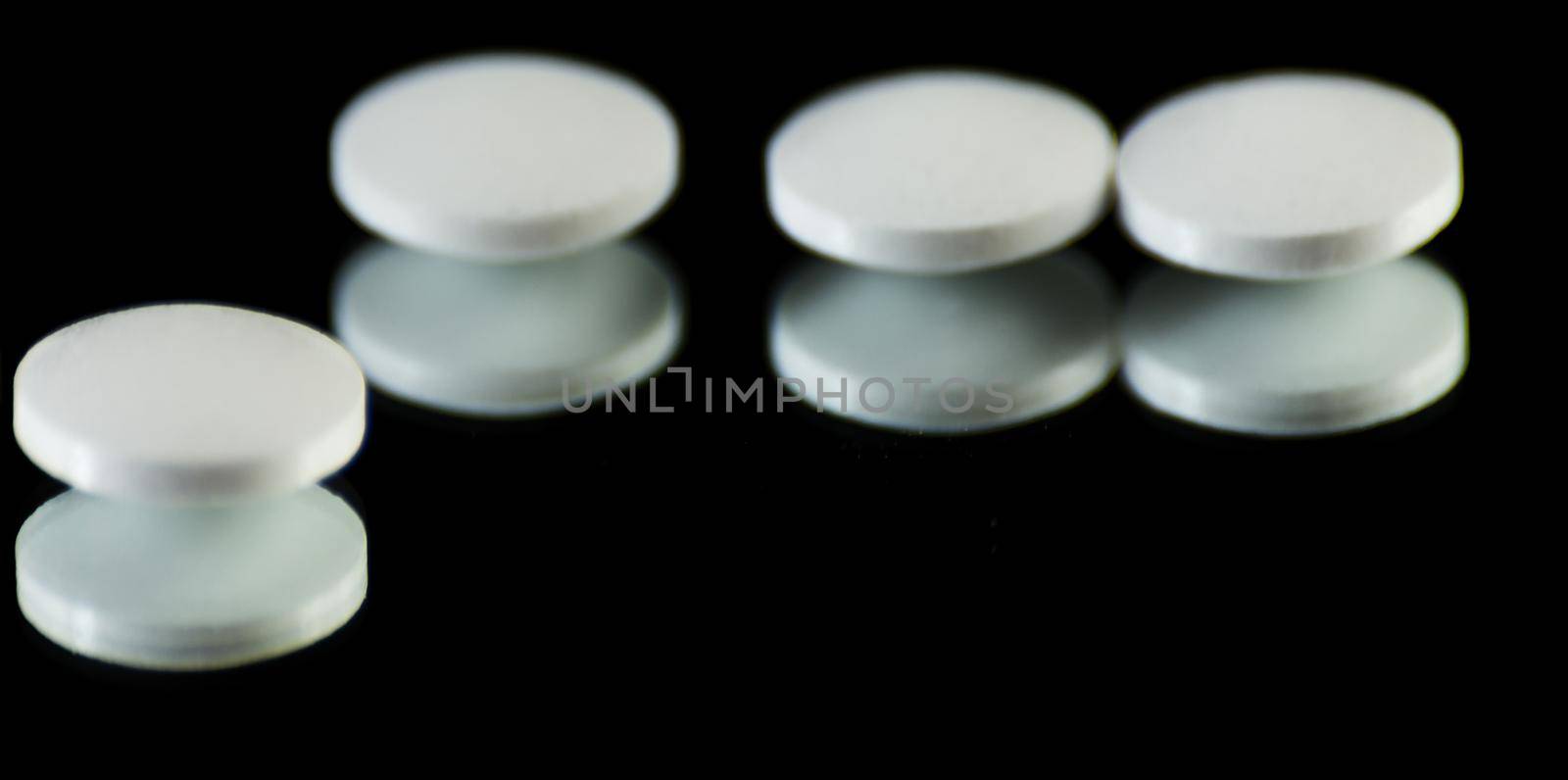scattered tablets on a black background, pills reflected in the mirror, medicine