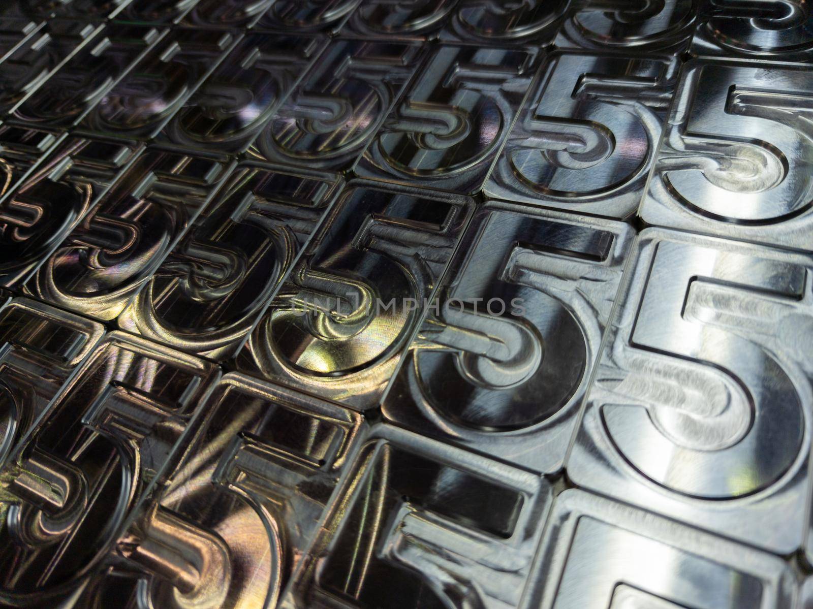 shiny metal machined digit 5 plates tiled tightly - close-up full frame background