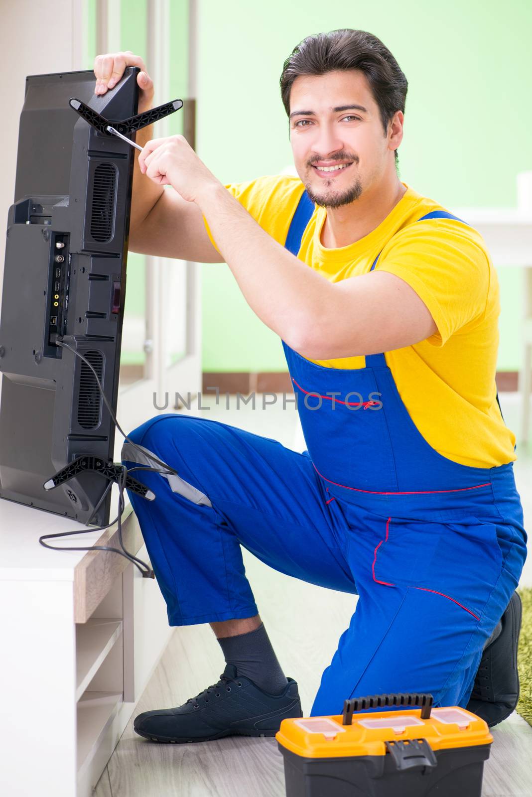 Male professional serviceman repairing tv at home