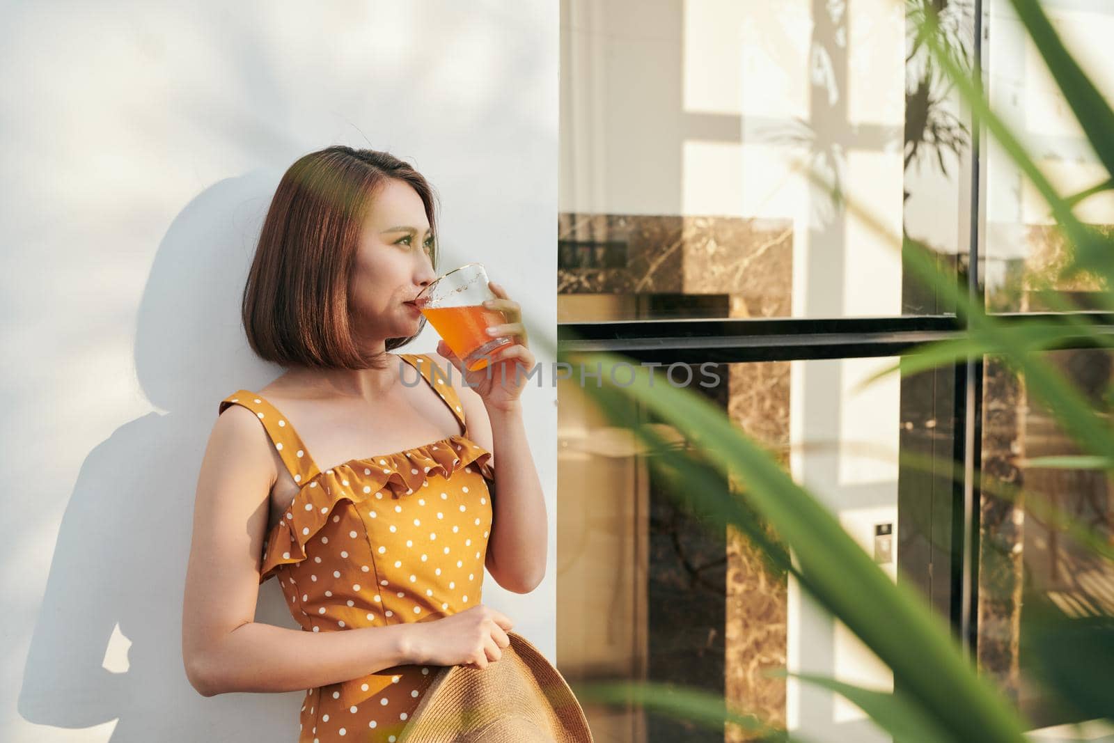 Happy summer woman enjoying orange juice behind the wall by makidotvn