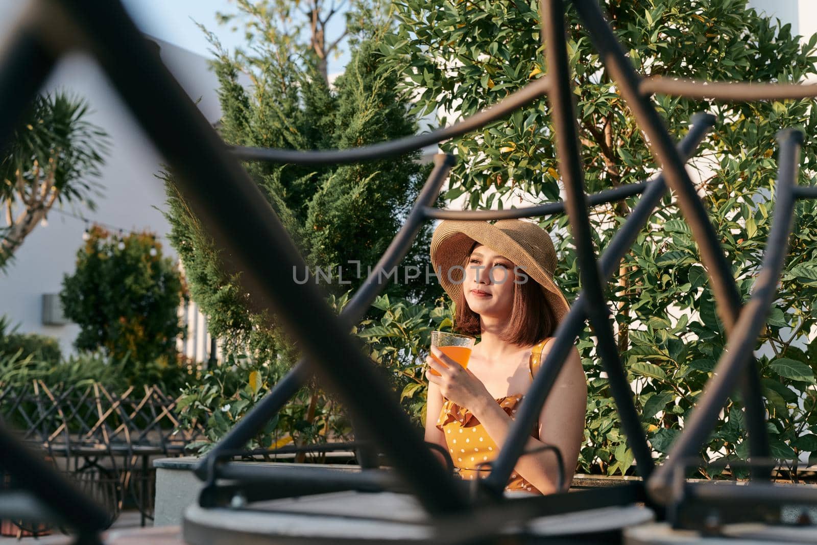 Portrait of young Asian girl sitting and drinking orange juice in the park.
