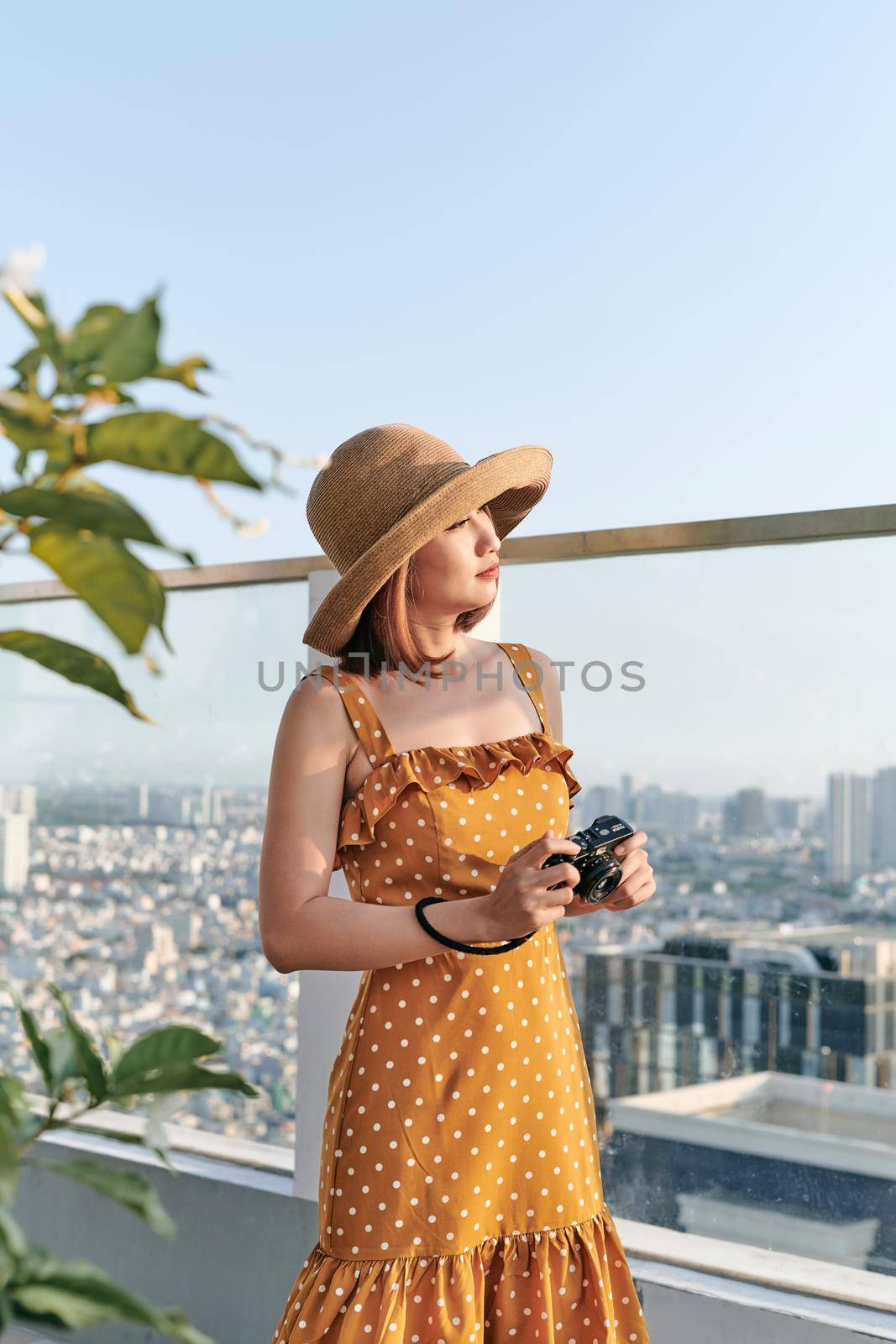 Young Asian girl standing on roof top and using camera to take picture. Summer concept. by makidotvn