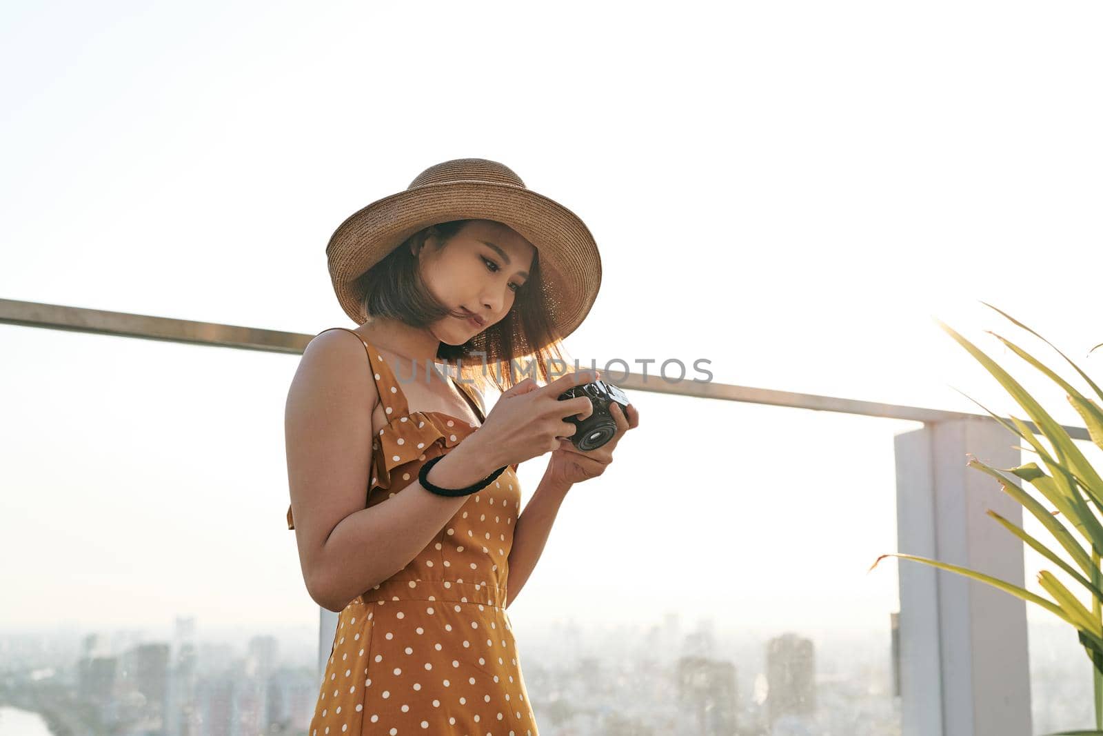 Young beautiful Asian traveler woman using digital compact camera and smile by makidotvn