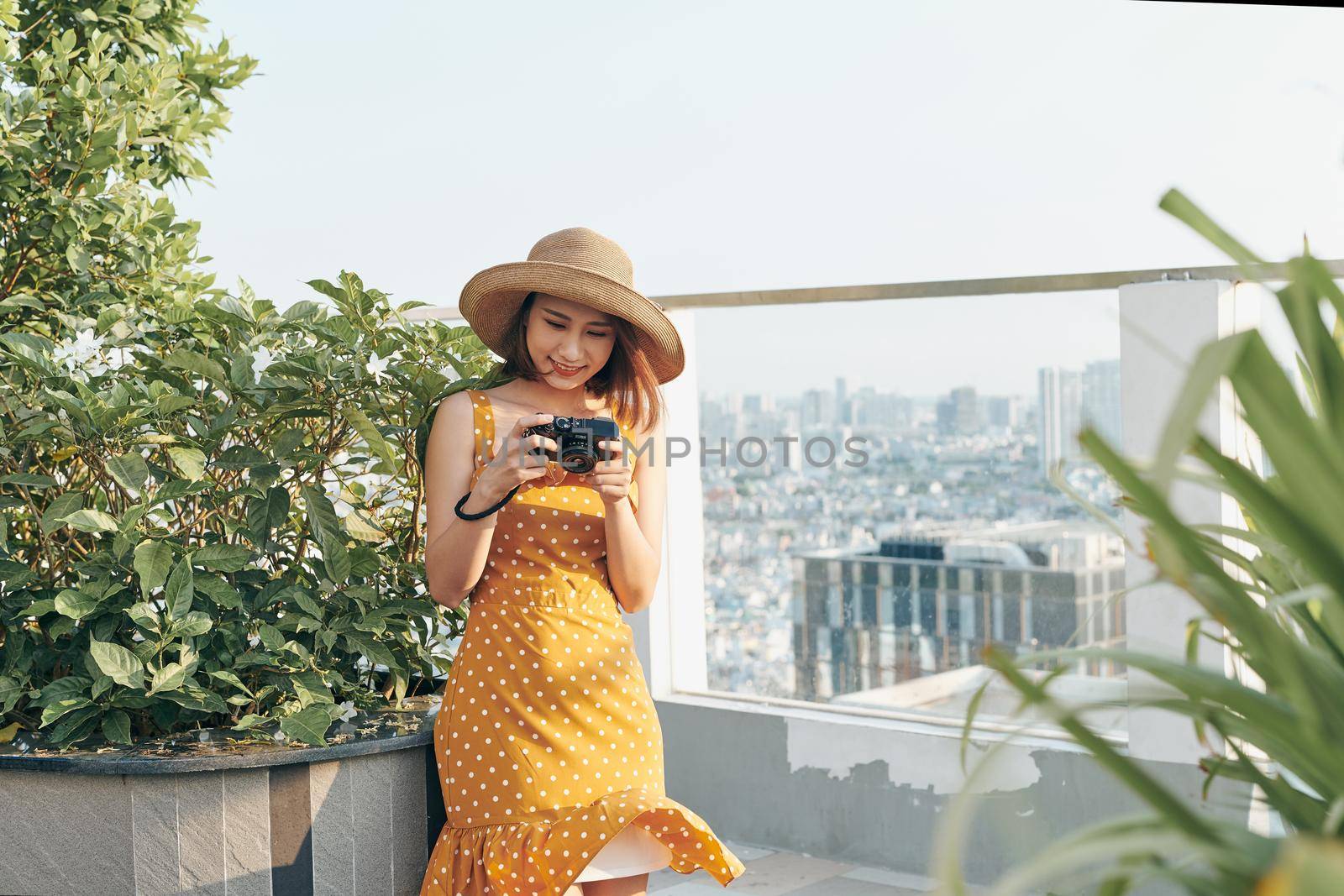 Young Asian girl standing on roof top and using camera to take picture. Summer concept.