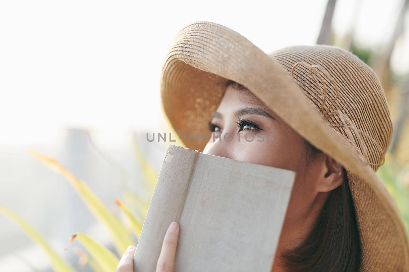 Portrait of Asian woman hiding behind book by makidotvn