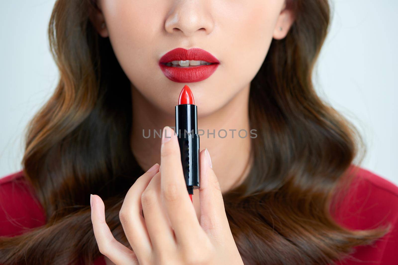 Detail of a beautiful woman applying lipstick