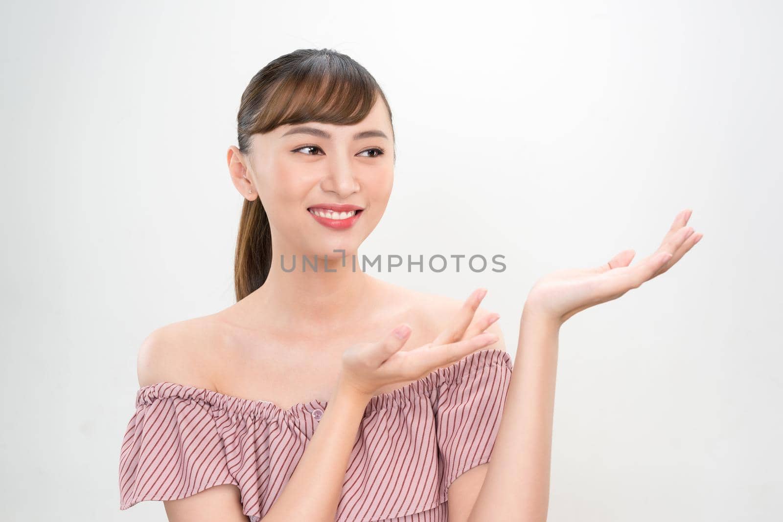 Woman shows something with hand. Pretty girl with white copy space
