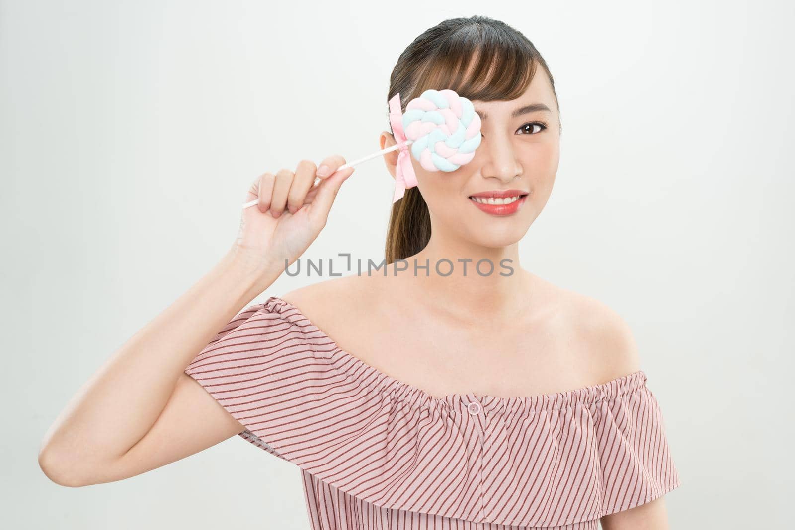 Short hair asian young beautiful woman smiling, covering her eye with lollipop. isolated over white background.