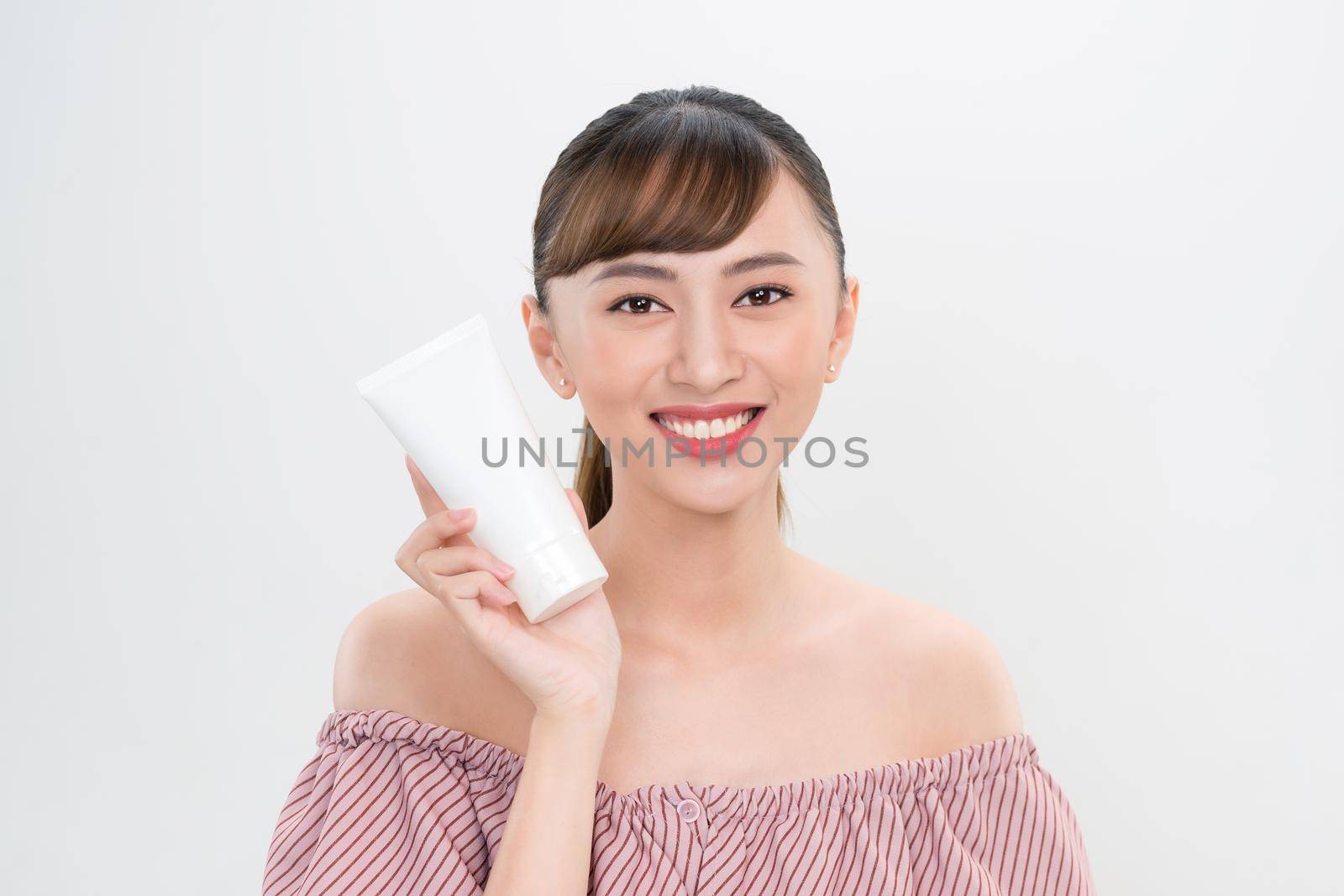smiling young woman showing skincare products 