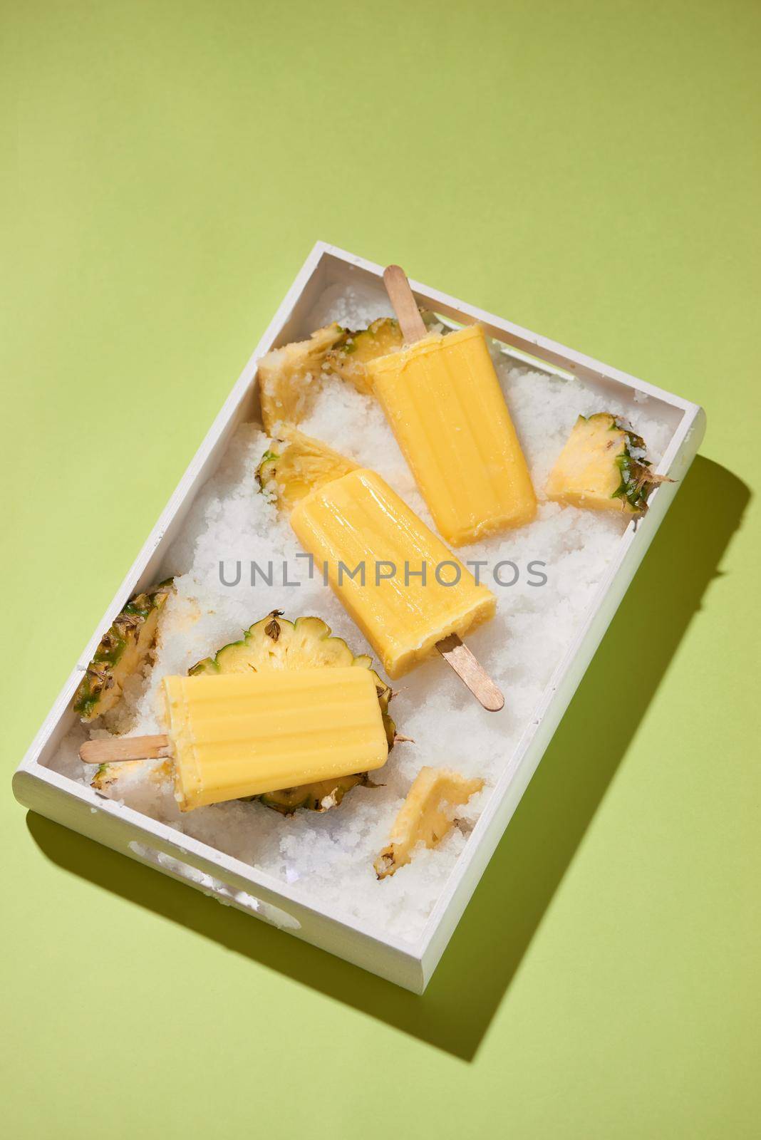 Yellow fruit popsicles on a tray top view, summer mood by makidotvn