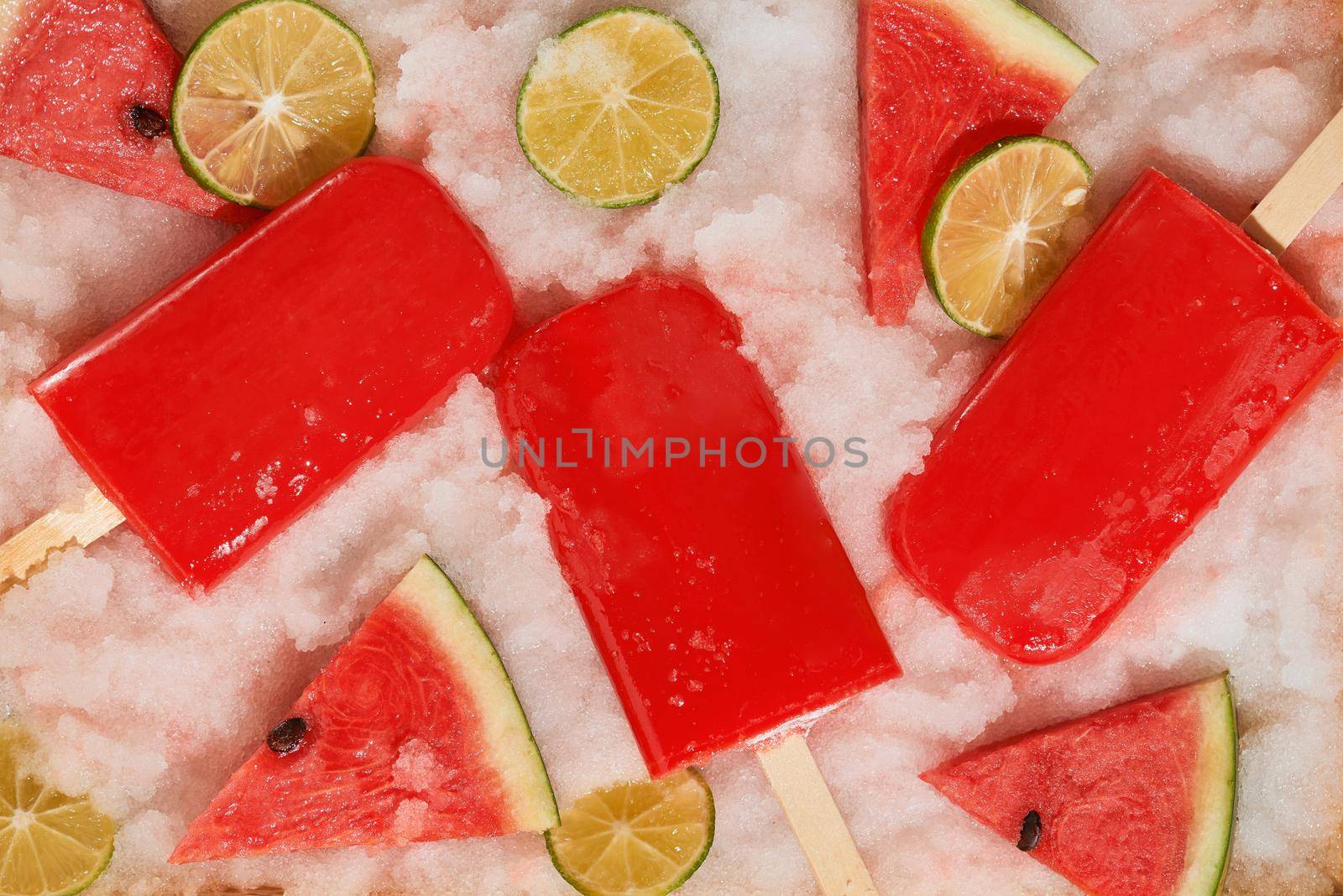 Watermelon popsicles and sliced lemon on ice filled tray 