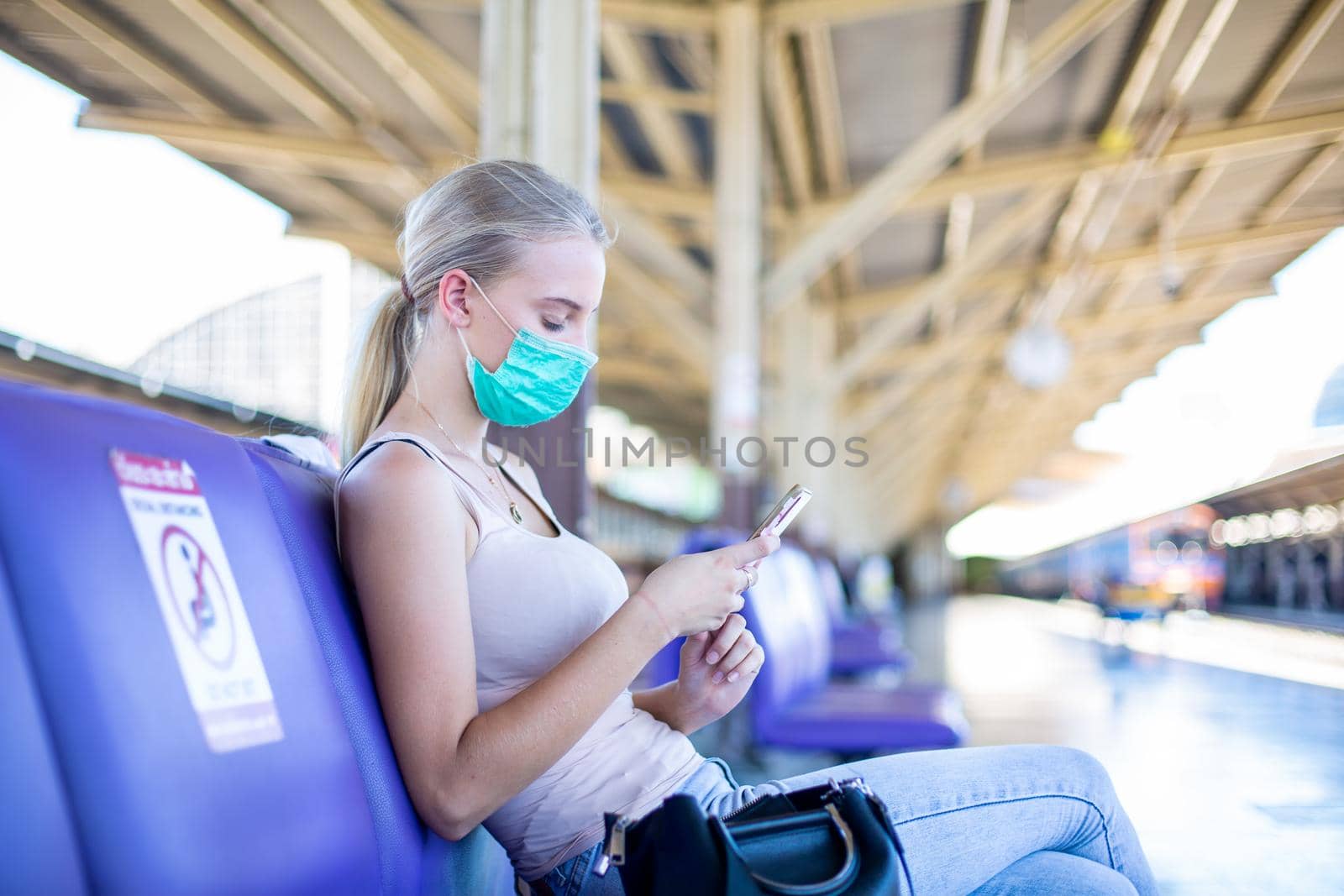 young woman with face mask waiting in vintage train, relaxed and carefree at the station platform in Bangkok, Thailand before catching a train. Travel photography. Lifestyle.