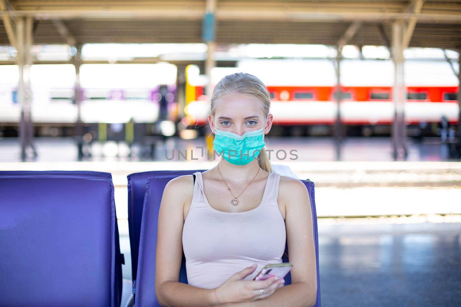 young woman with face mask waiting in vintage train, relaxed and carefree at the station platform in Bangkok, Thailand before catching a train. Travel photography. Lifestyle.