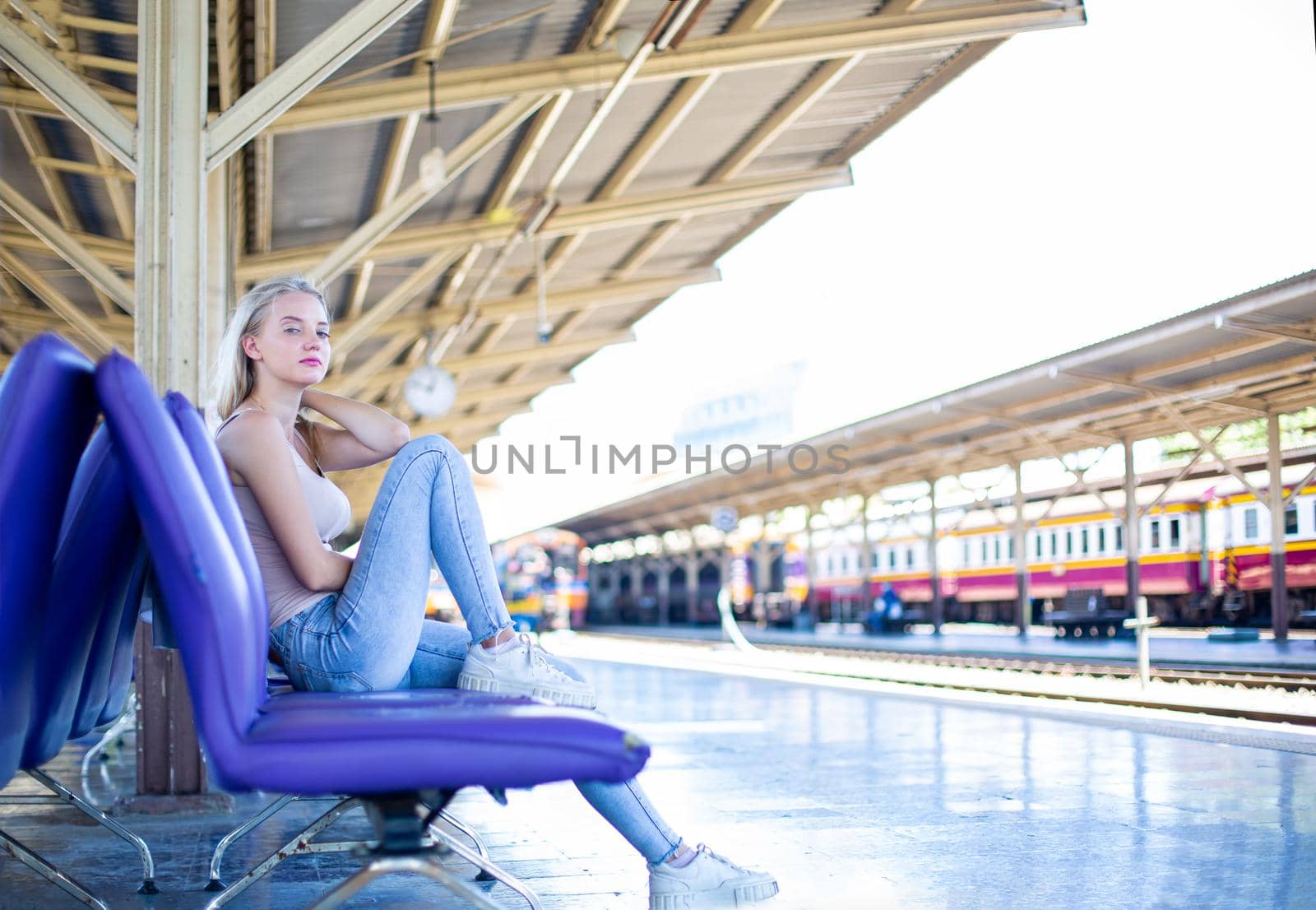 young woman waiting in vintage train, relaxed and carefree at the station platform in Bangkok, Thailand before catching a train. Travel photography. Lifestyle.