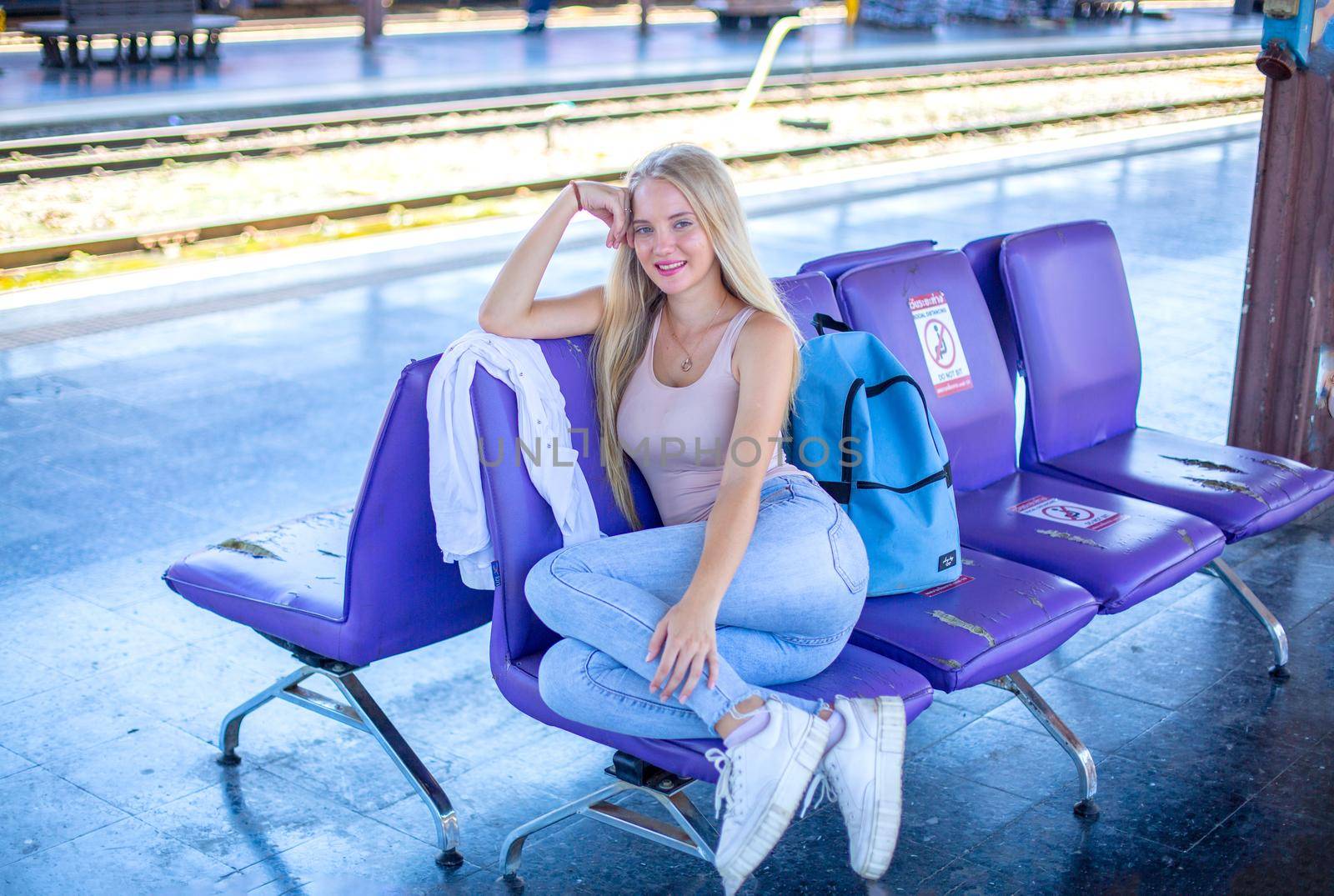 young woman waiting in vintage train, relaxed and carefree at the station platform in Bangkok, Thailand before catching a train. Travel photography. Lifestyle.