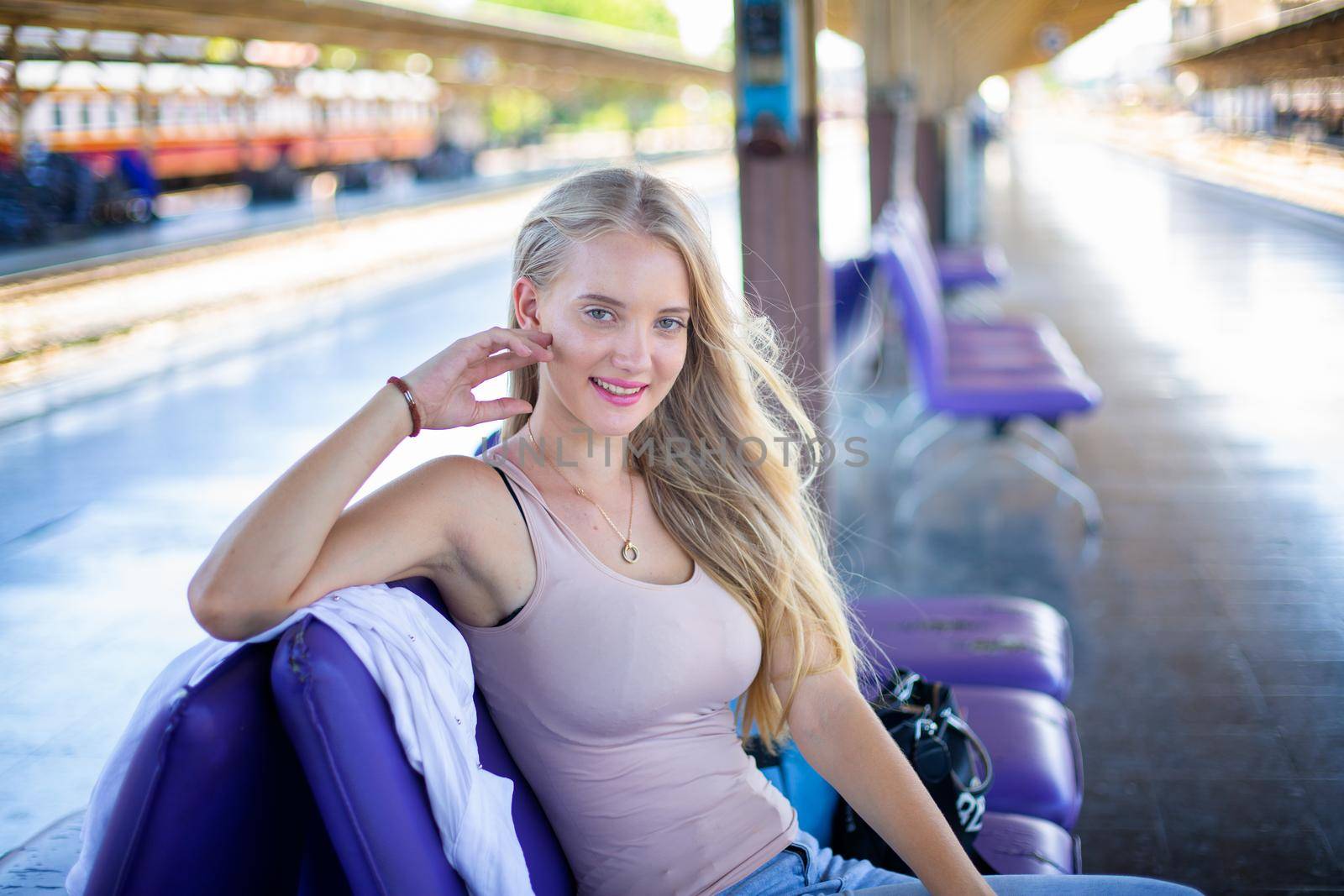 young woman waiting in vintage train, relaxed and carefree at the station platform in Bangkok, Thailand before catching a train. Travel photography. Lifestyle.