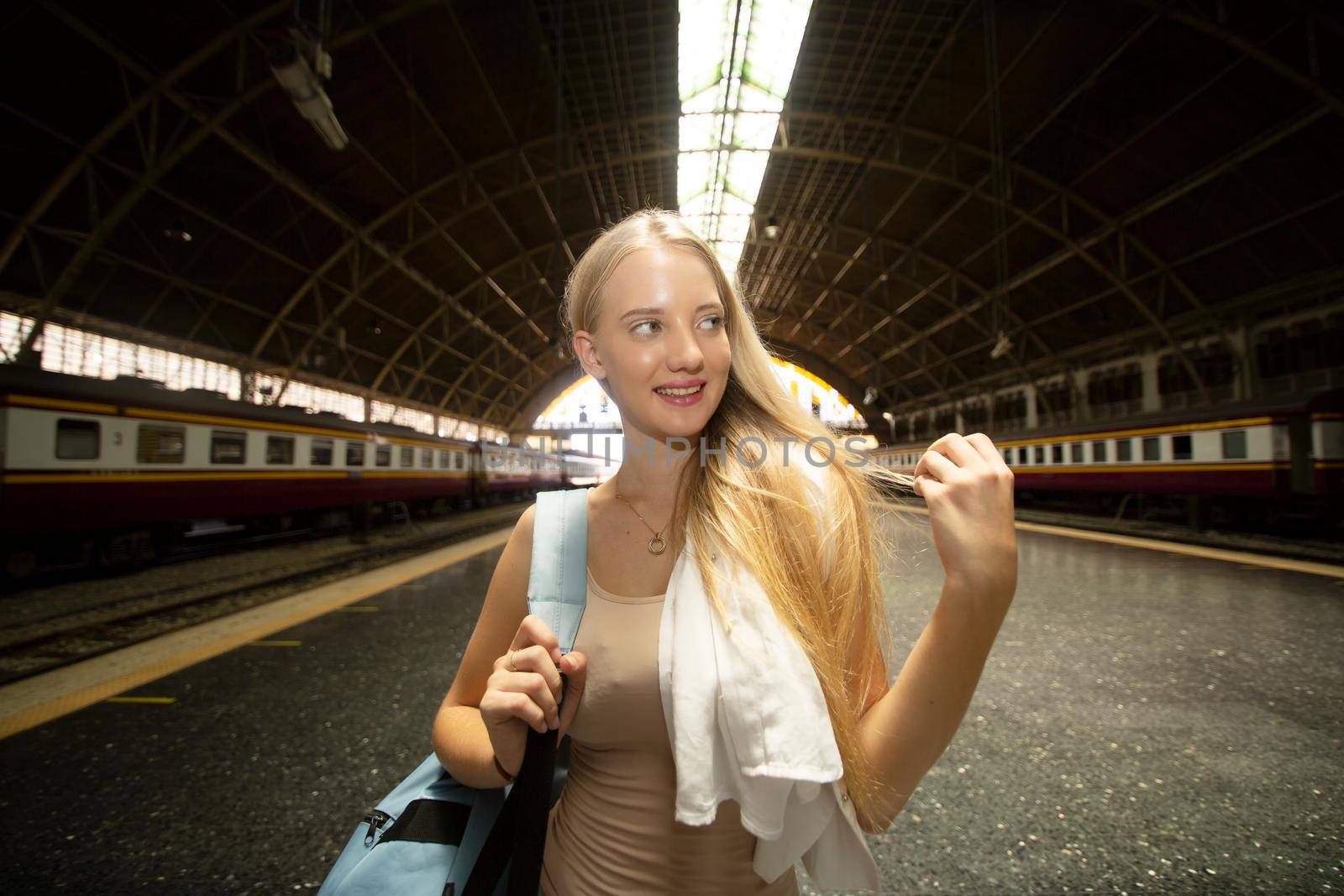 young woman waiting in vintage train, relaxed and carefree at the station platform in Bangkok, Thailand before catching a train. Travel photography. Lifestyle.