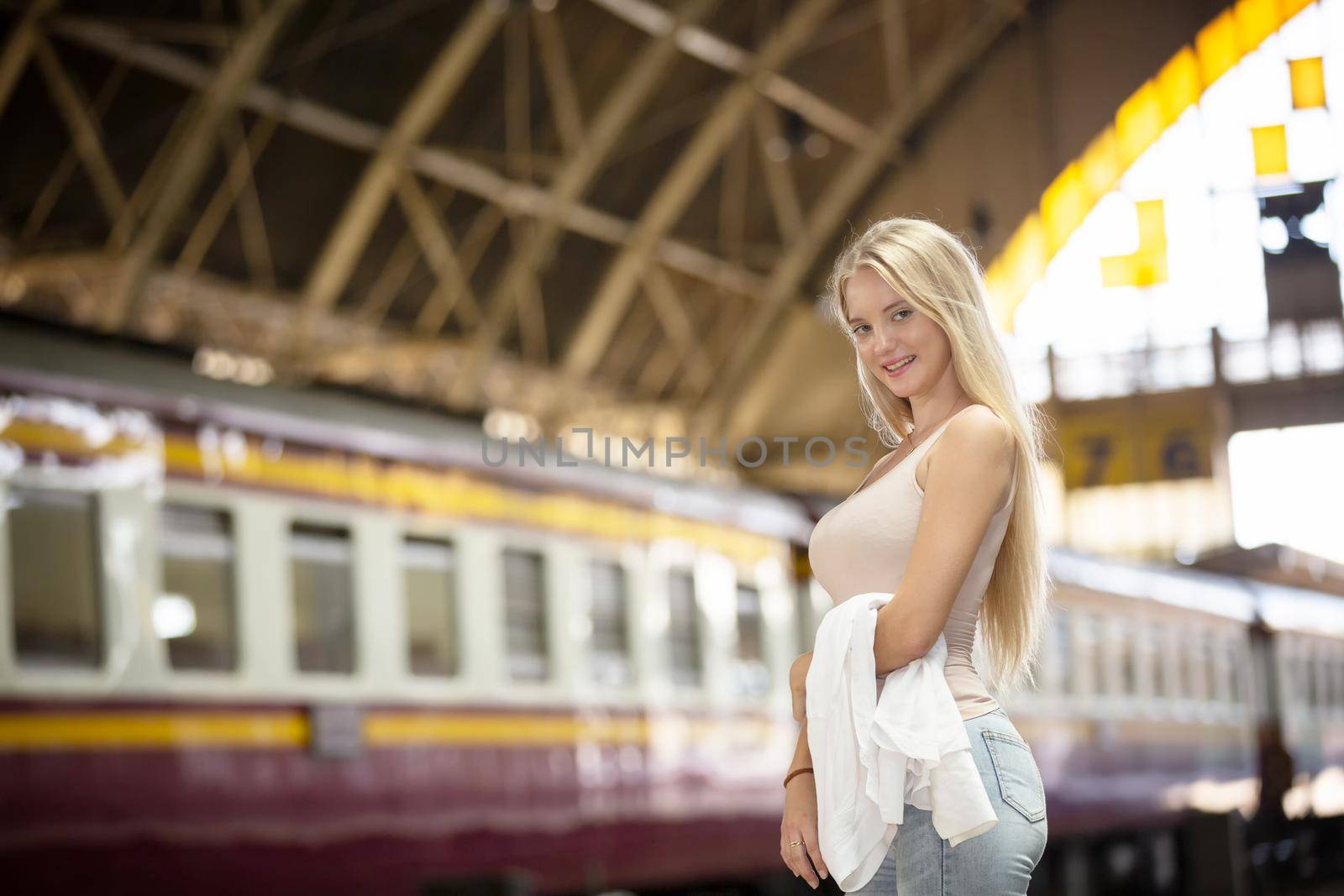 young woman waiting in vintage train, relaxed and carefree at the station platform in Bangkok, Thailand before catching a train. Travel photography. Lifestyle.