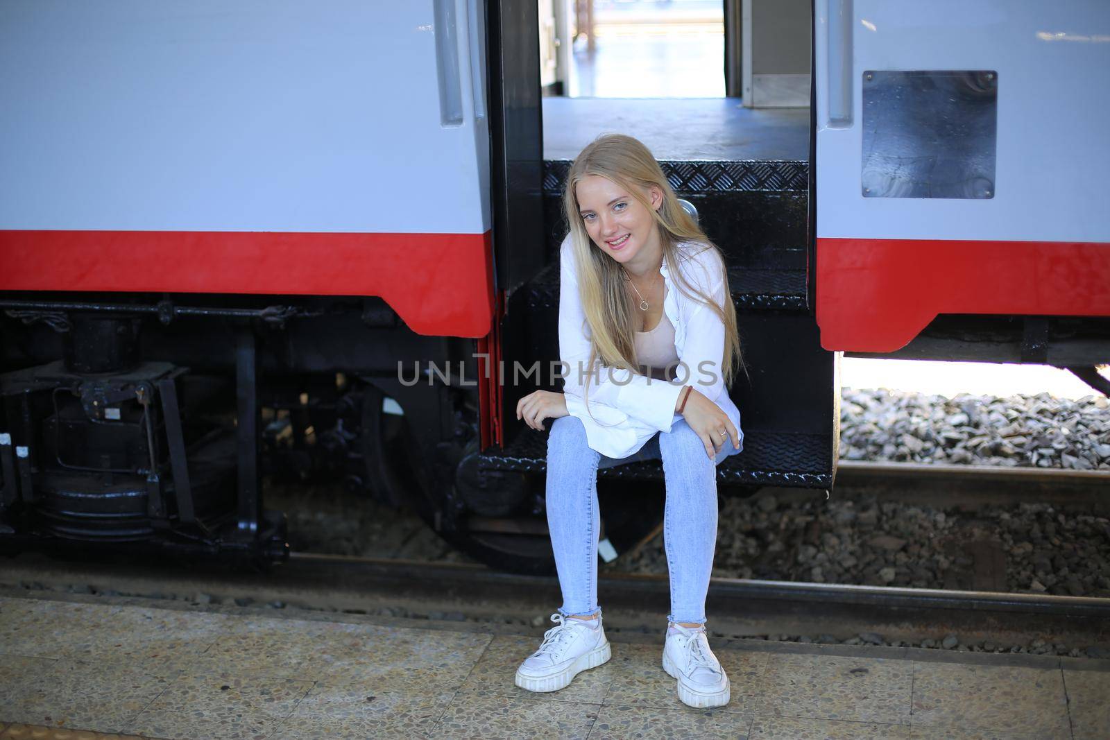 young woman waiting in vintage train, relaxed and carefree at the station platform in Bangkok, Thailand before catching a train. Travel photography. Lifestyle.