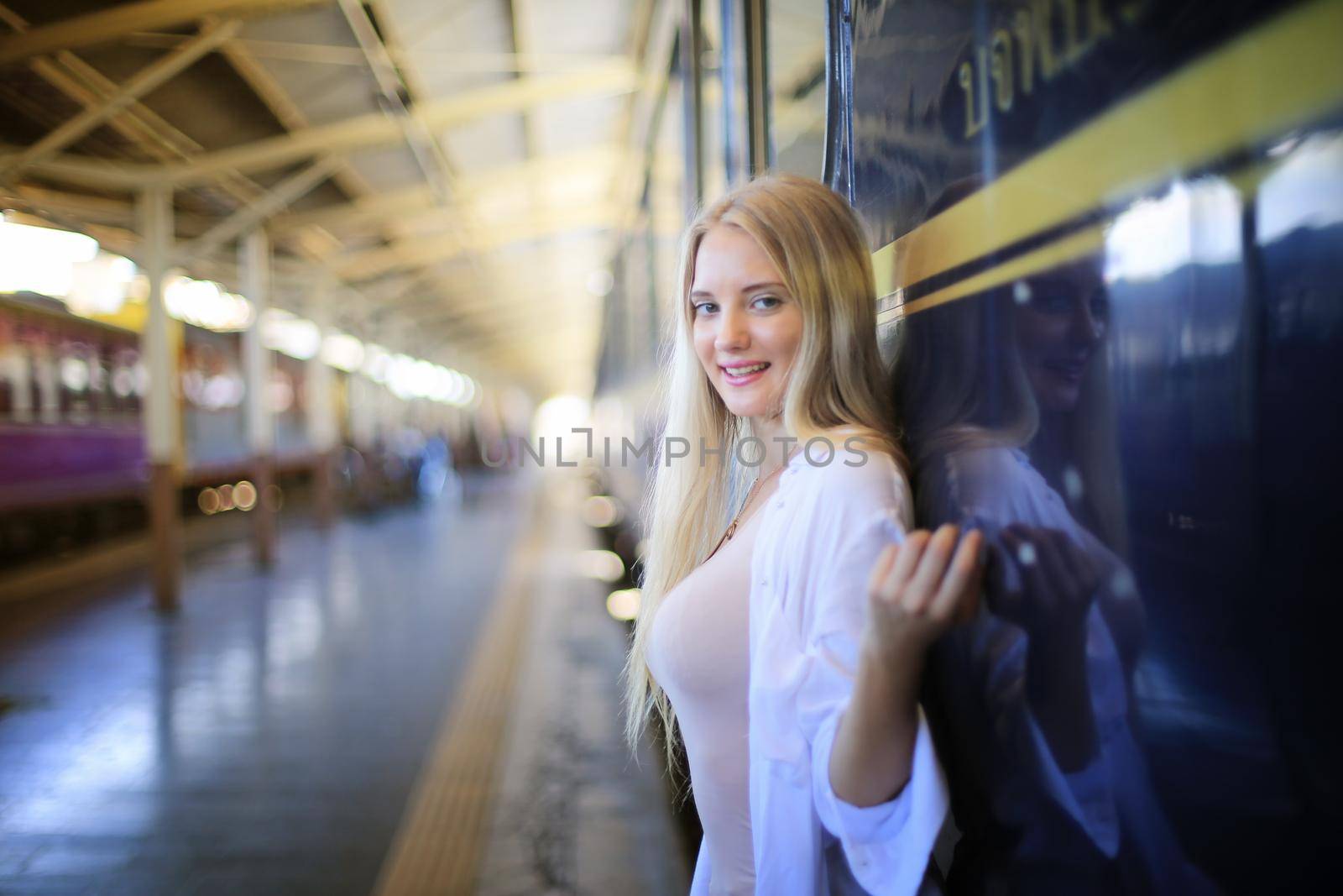 young woman waiting in vintage train, relaxed and carefree at the station platform in Bangkok, Thailand before catching a train. Travel photography. Lifestyle.