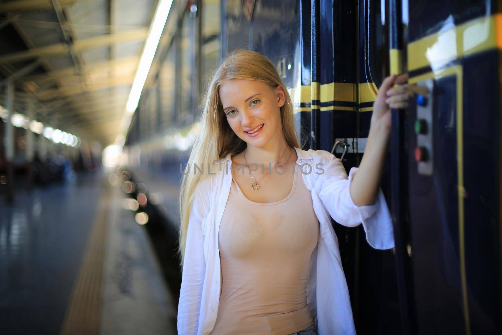 young woman waiting in vintage train, relaxed and carefree at the station platform in Bangkok, Thailand before catching a train. Travel photography. Lifestyle.