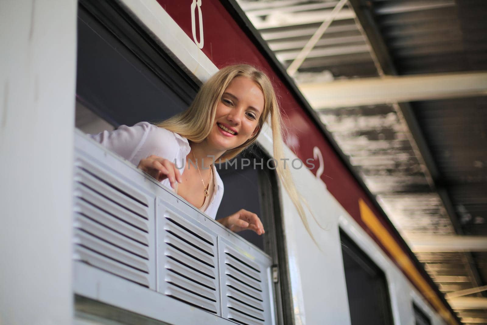 young woman waiting in vintage train, relaxed and carefree at the station platform in Bangkok, Thailand before catching a train. Travel photography. Lifestyle.