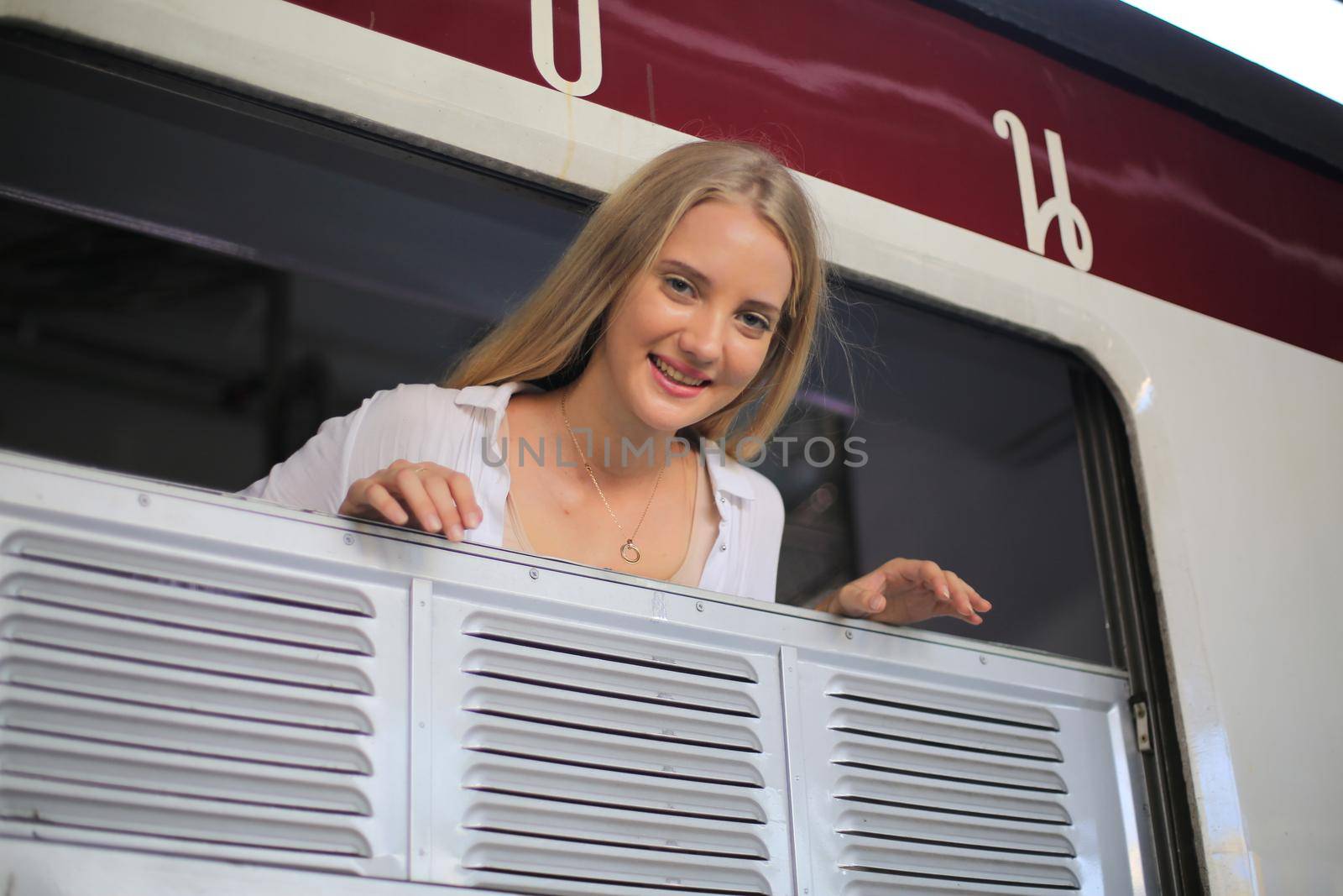 young woman waiting in vintage train, relaxed and carefree at the station platform in Bangkok, Thailand before catching a train. Travel photography. Lifestyle.