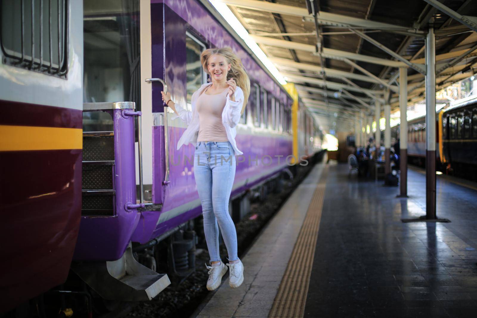 young woman waiting in vintage train, relaxed and carefree at the station platform in Bangkok, Thailand before catching a train. Travel photography. Lifestyle.