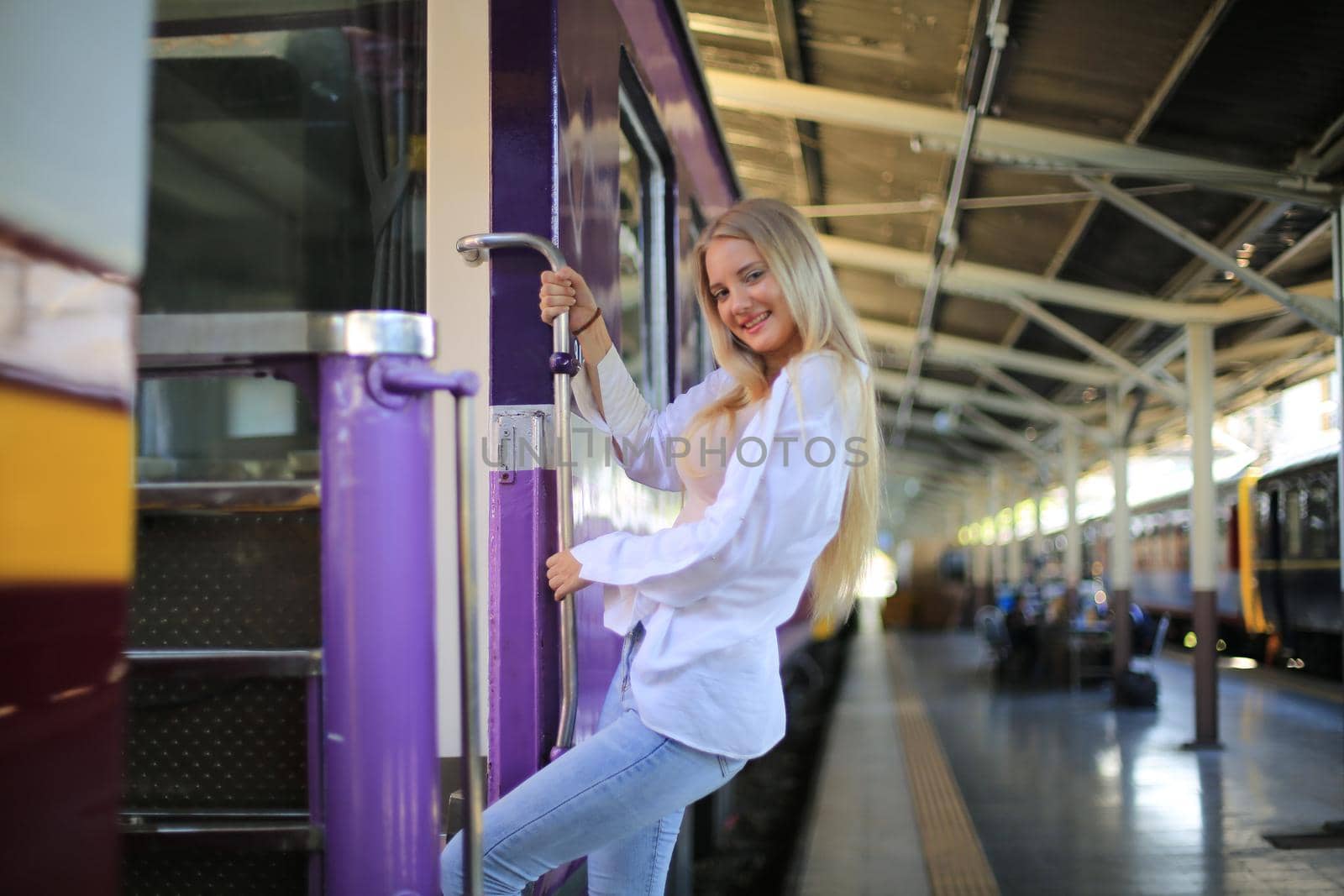 young woman waiting in vintage train, relaxed and carefree at the station platform in Bangkok, Thailand before catching a train. Travel photography. Lifestyle.