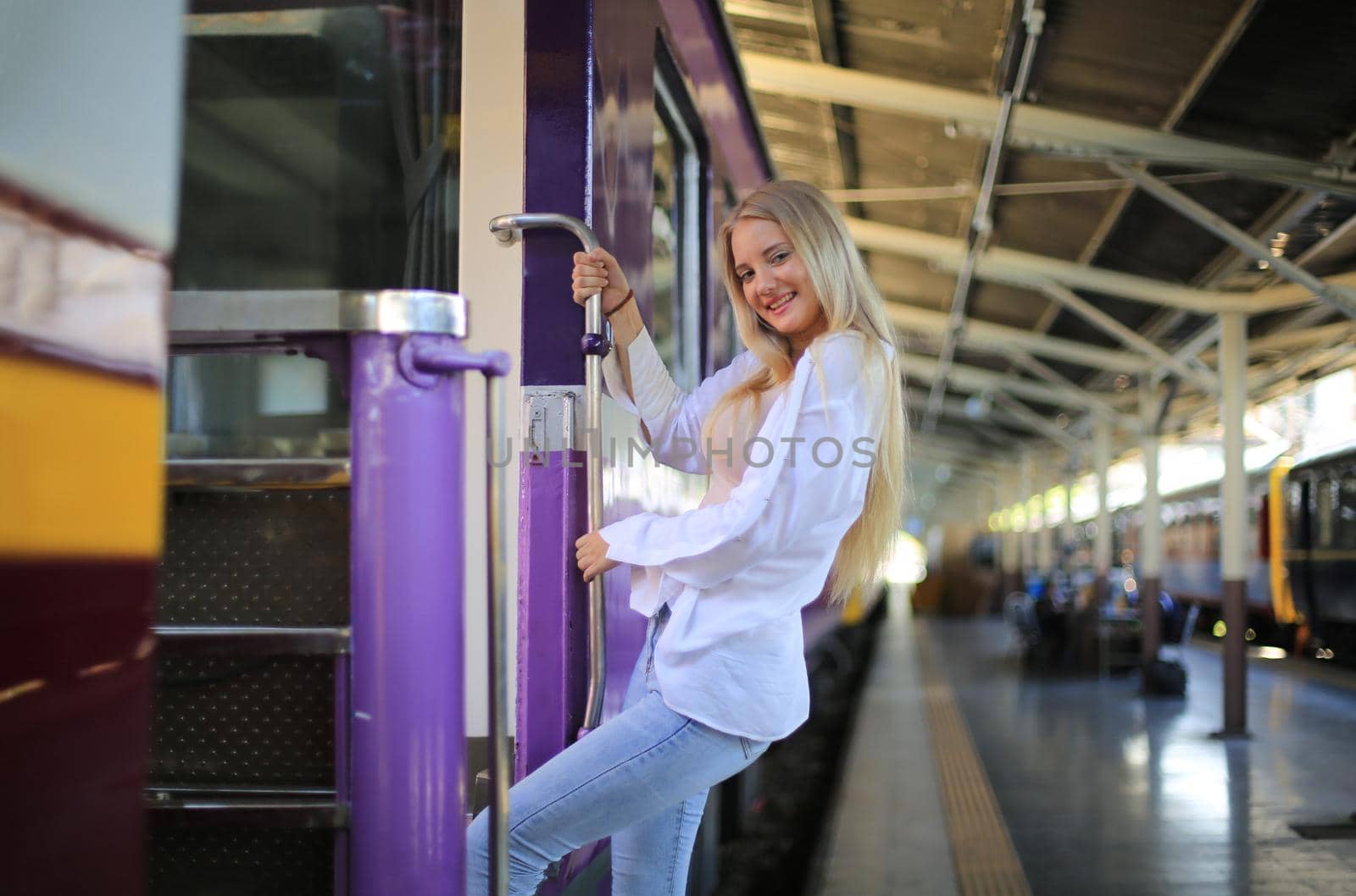 young woman waiting in vintage train, relaxed and carefree at the station platform in Bangkok, Thailand before catching a train. Travel photography. Lifestyle.