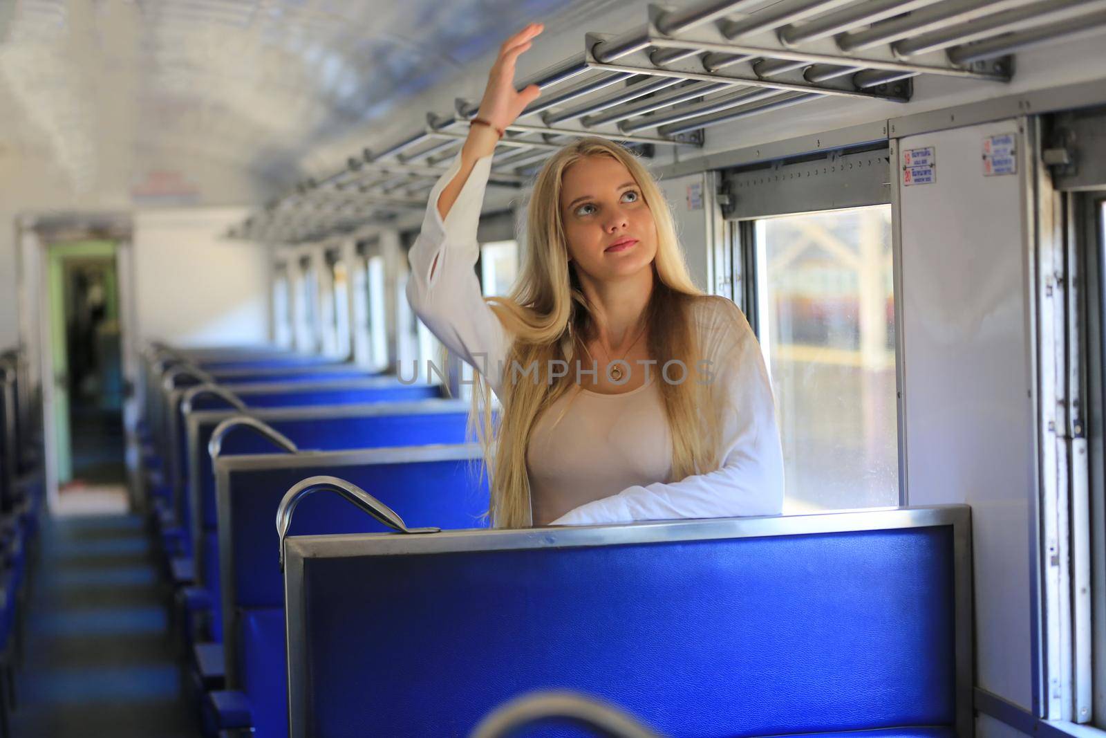 young woman waiting in vintage train, relaxed and carefree at the station platform in Bangkok, Thailand before catching a train. Travel photography. Lifestyle.