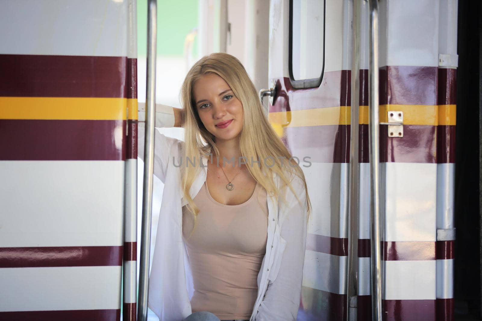 young woman waiting in vintage train, relaxed and carefree at the station platform in Bangkok, Thailand before catching a train. Travel photography. Lifestyle.