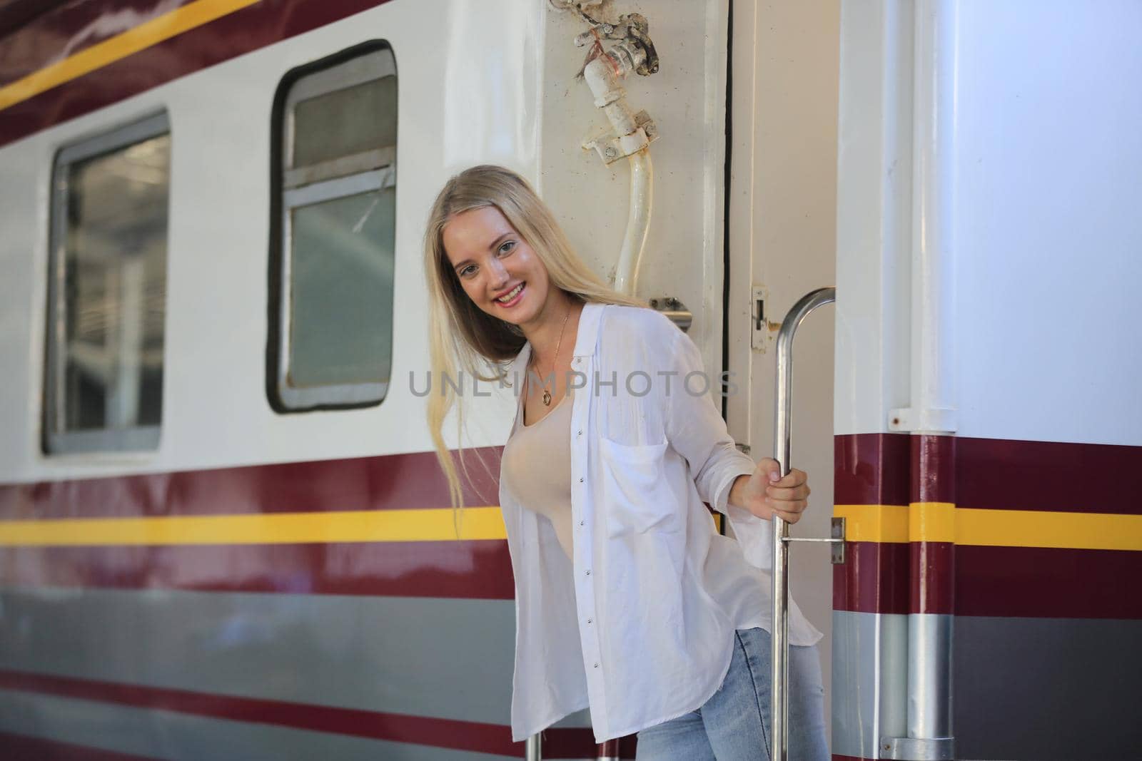 young woman waiting in vintage train, relaxed and carefree at the station platform in Bangkok, Thailand before catching a train. Travel photography. Lifestyle.