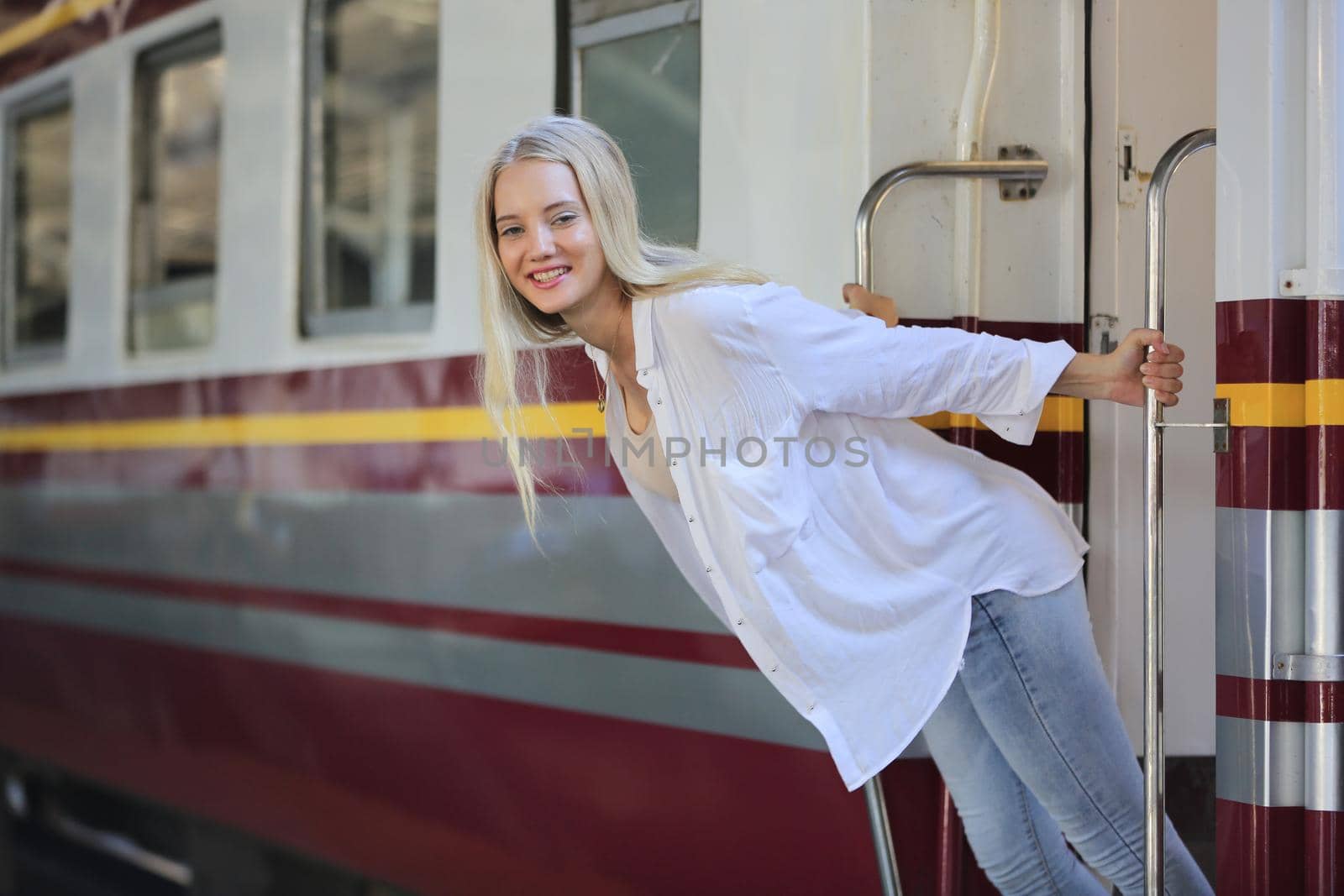 young woman waiting in vintage train, relaxed and carefree at the station platform in Bangkok, Thailand before catching a train. Travel photography. Lifestyle.