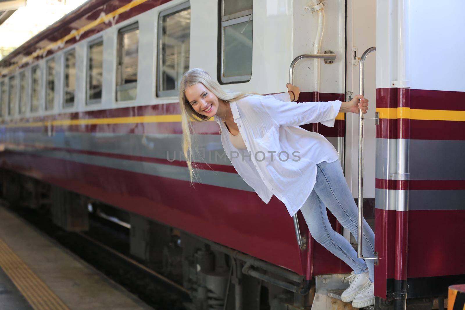 young woman waiting in vintage train, relaxed and carefree at the station platform in Bangkok, Thailand before catching a train. Travel photography. Lifestyle.