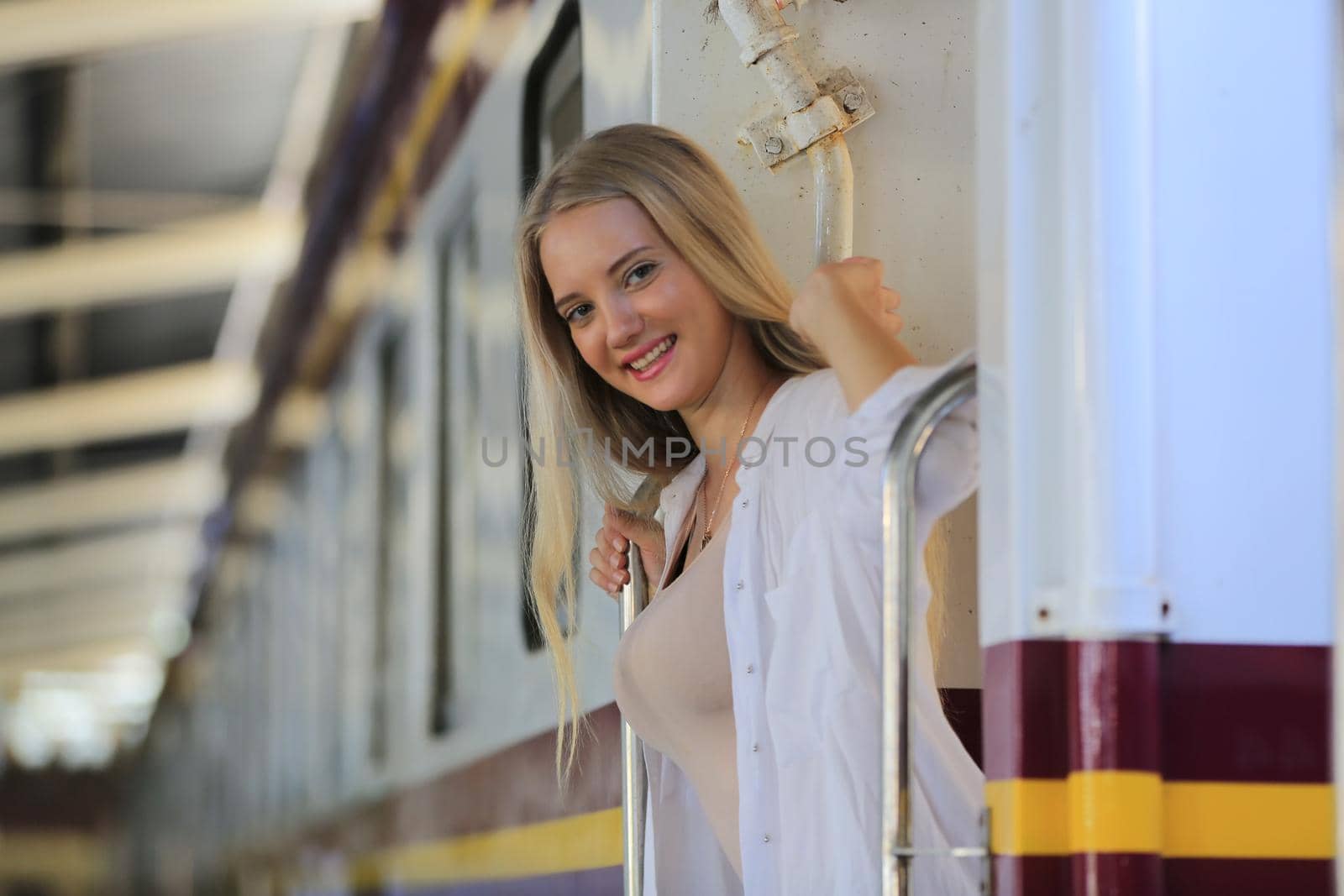 young woman waiting in vintage train, relaxed and carefree at the station platform in Bangkok, Thailand before catching a train. Travel photography. Lifestyle.