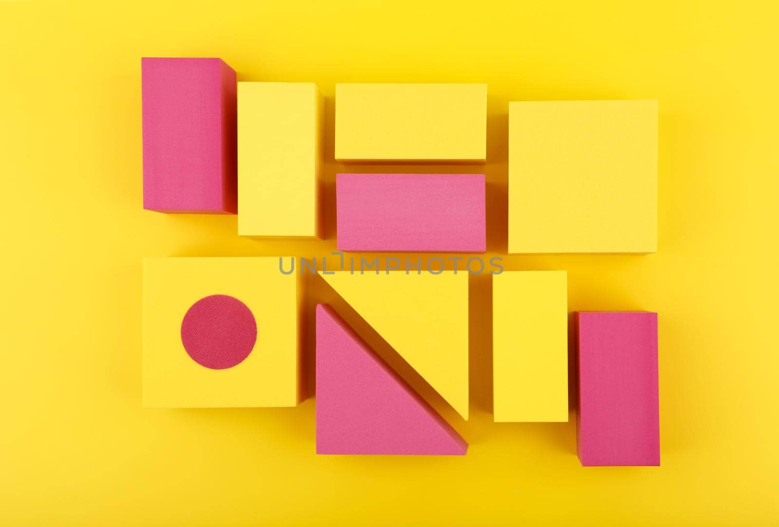 Creative duotone flat lay with yellow and pink geometric figures on yellow background. 