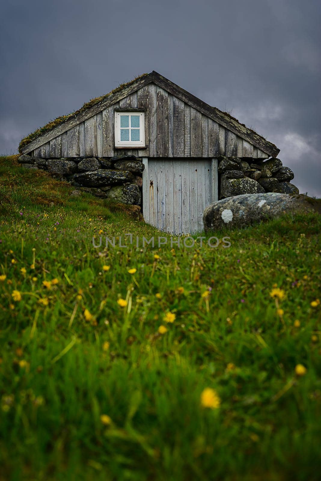 Old outhouse next to main house. Not in use today, is more of a museum object. Called 'Træet på Line'. Nice colors during the spring time, dark clouds in the horizon.