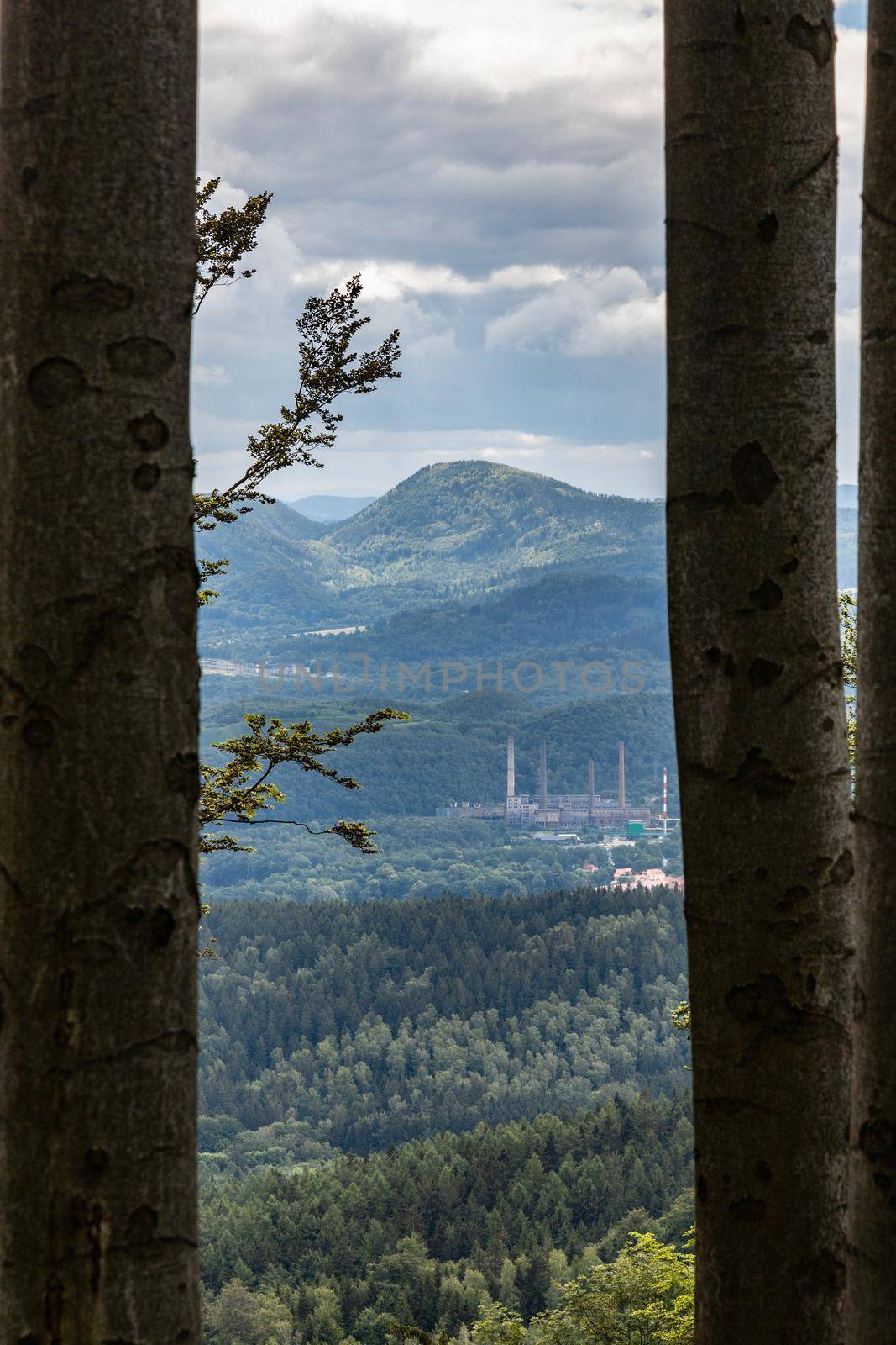 Landscape of hills and mountains over small city with factories between high trees