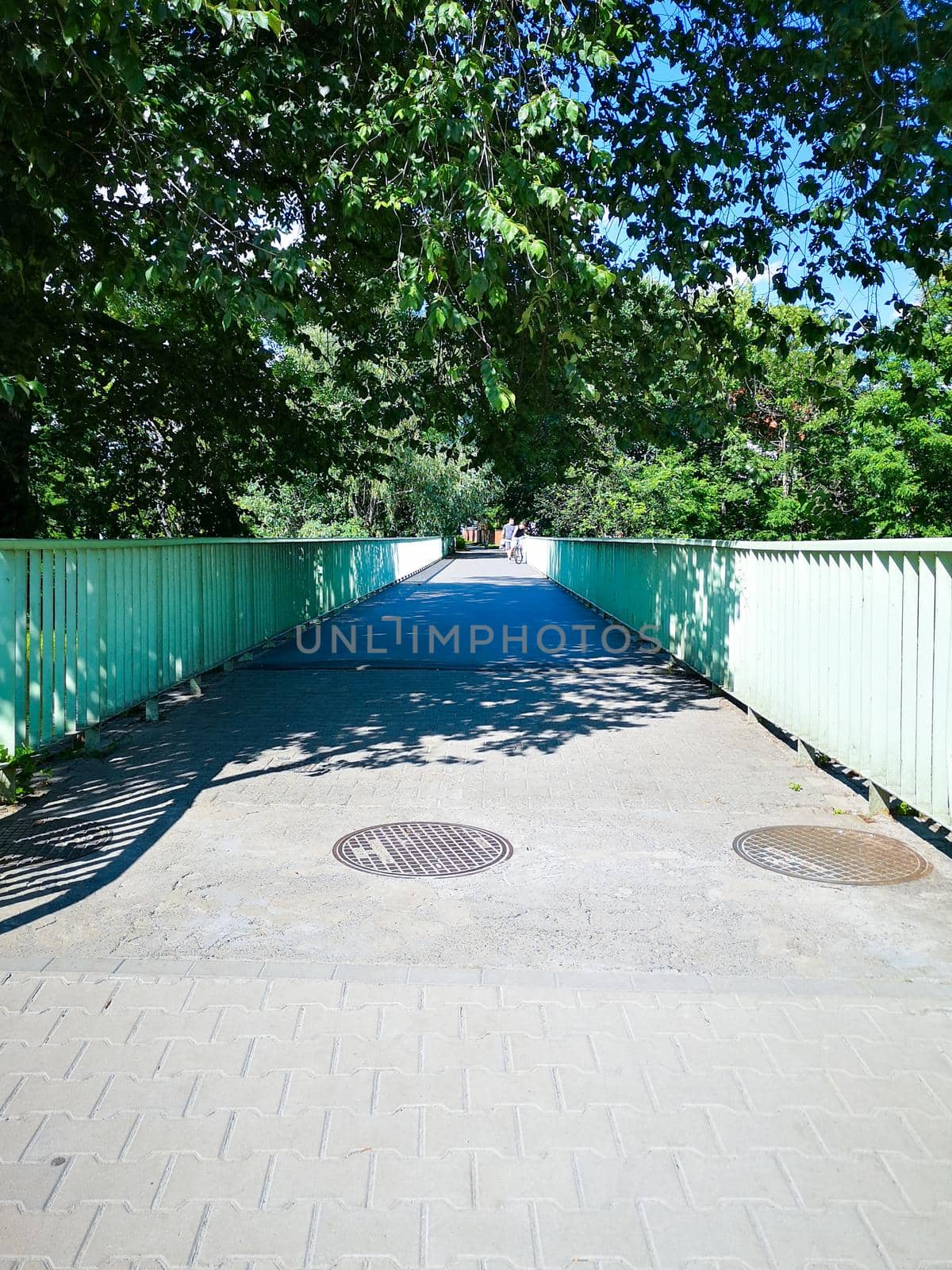 Long narrow concrete bridge with green metal railings on both sides