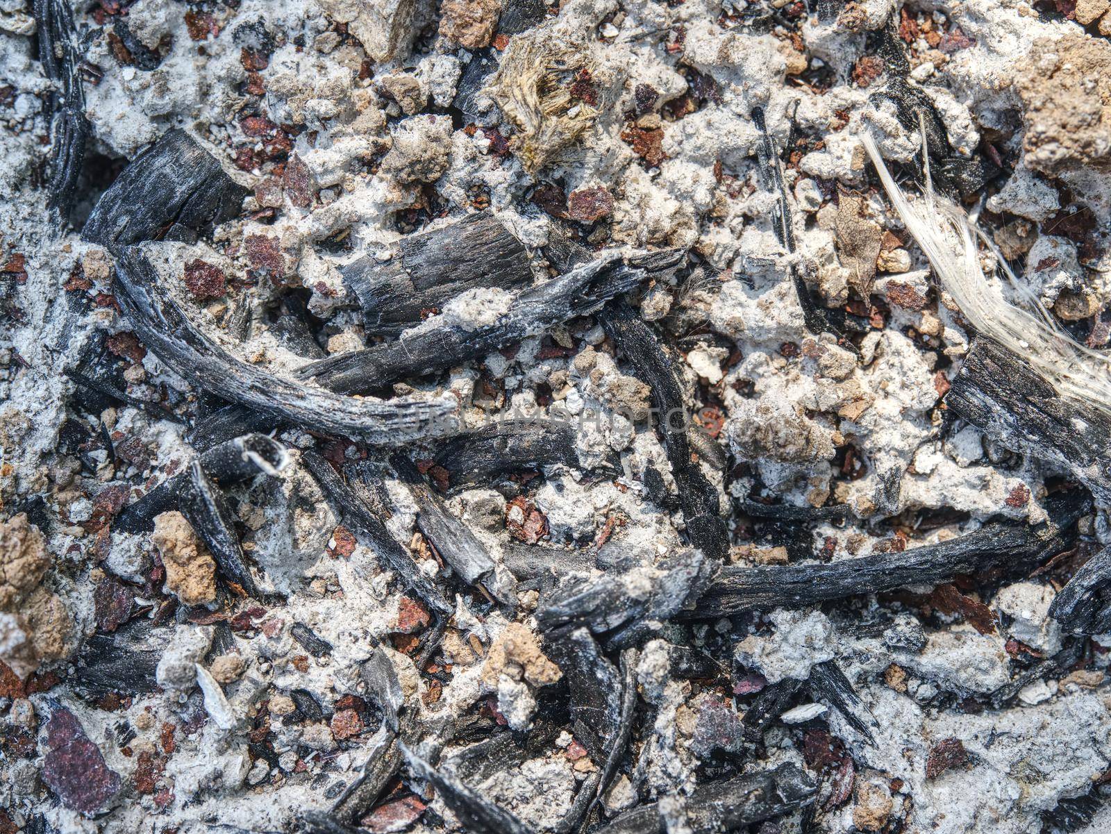 Ground with ash, coals and rusty iron plates on ground of burnt house.